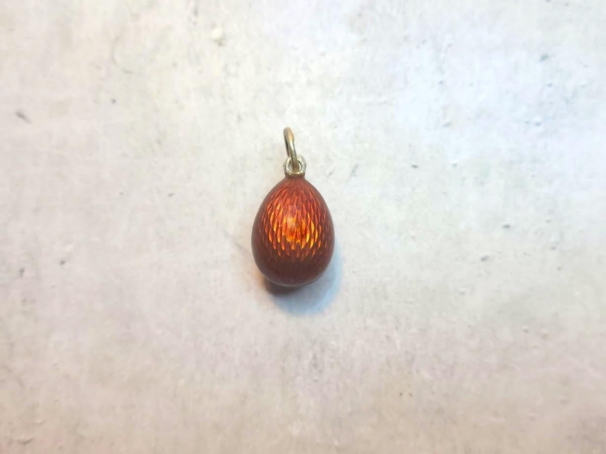We are pleased to present another unique item from our collection—an elegant miniature egg pendant adorned with guilloché enamel from the era of the Russian Empire. This exquisite piece was crafted in St. Petersburg by master Alfred Thielemann at