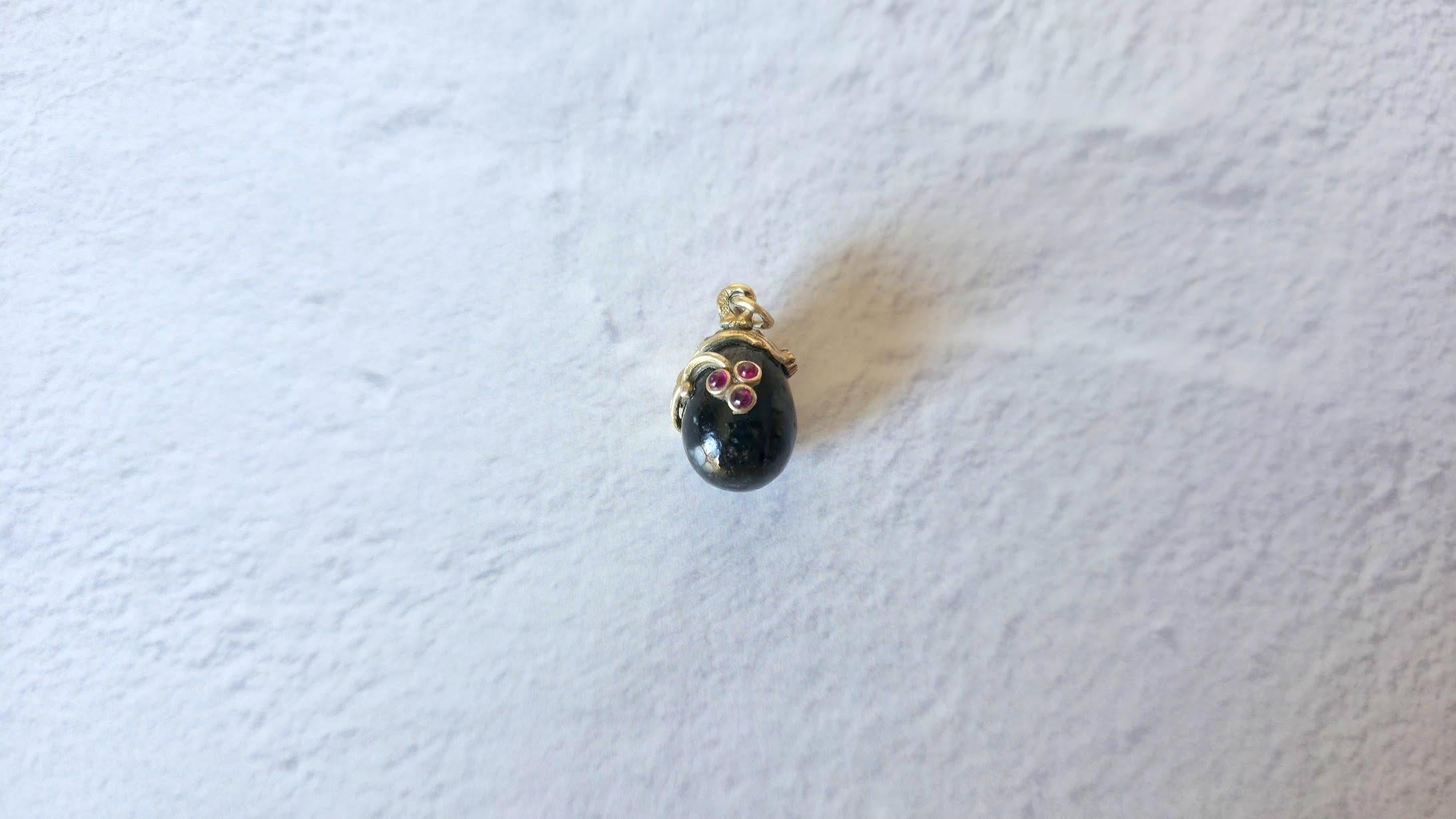 Scopri uno splendido ciondolo a forma di uovo in argento dorato con una nefrite nera, impreziosita da un disegno floreale asimmetrico dorato con tre delicati rubini e un diamante. Questo incantevole gioiello è un vero capolavoro.
Ciò che distingue