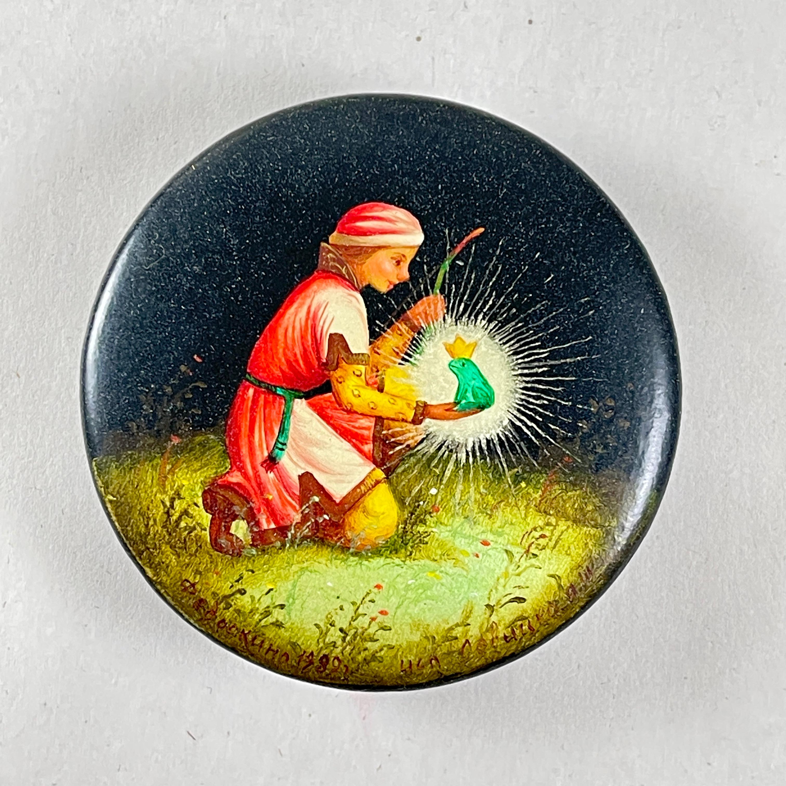 Scatola vintage in cartapesta dipinta a mano raffigurante il Principe Ivan e la Principessa Ranocchio, epoca URSS, Russia, circa 1990-2000.

La piccola scatola rotonda mostra un'originale miniatura di lacca tradizionale russa su cartapesta, che
