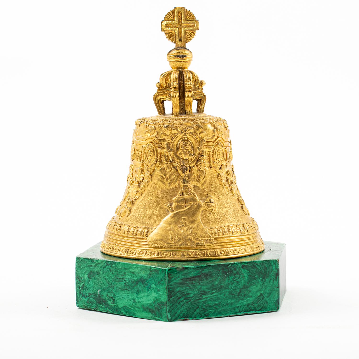 Elegant Russian bronze desk bell on a hexagonal base of malachite.
This bell is a miniature representation of the Brobdingnagian Tsar Bell in Moscow (also known as the Tsarsky Kolokol, Tsar Kolokol III, or Royal Bell).
Crafted in gilt bronze the