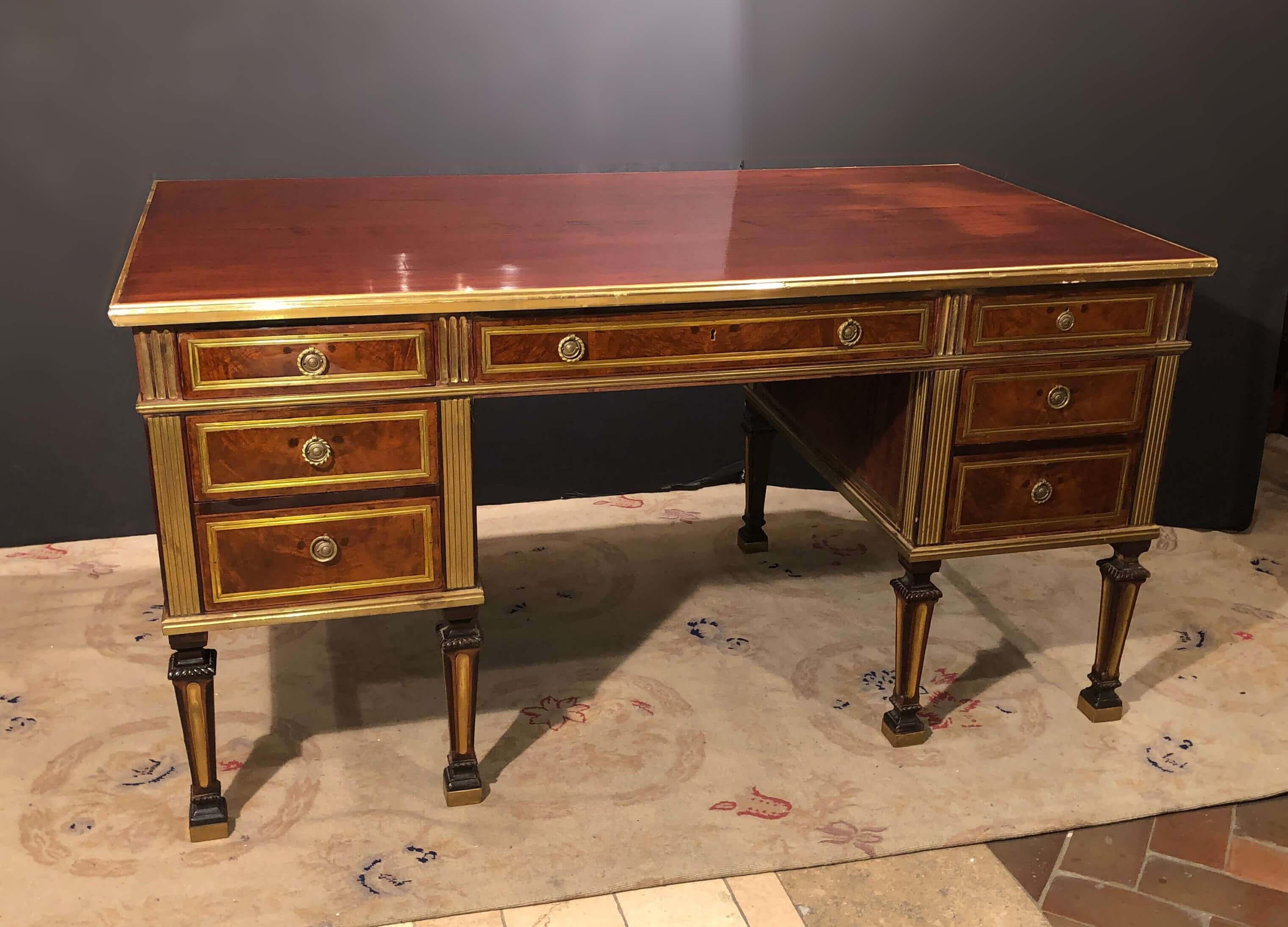 A large Russian neoclassic mahogany desk with brass trim and moldings, on square tapered and fluted legs.