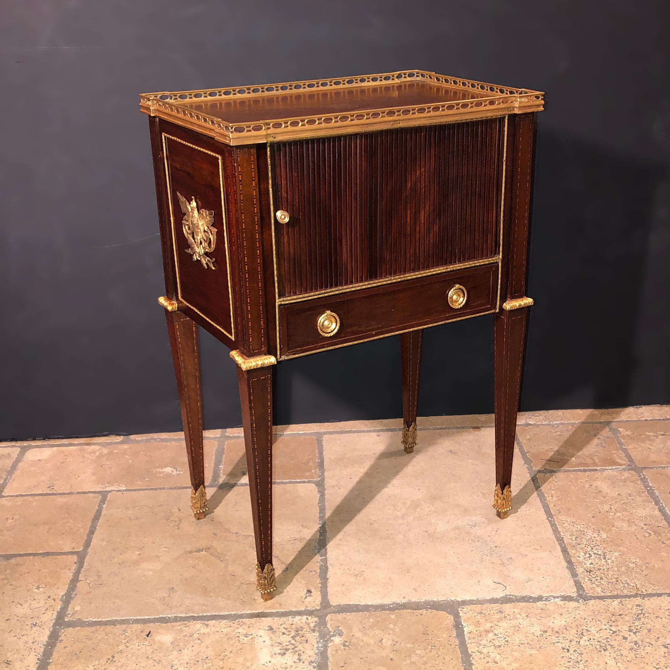 A fine Russian neoclassic mahogany end table with a tooled leather top, pierced bronze gallery, brass trim, tambour door with a single drawer and raised on tapered legs.