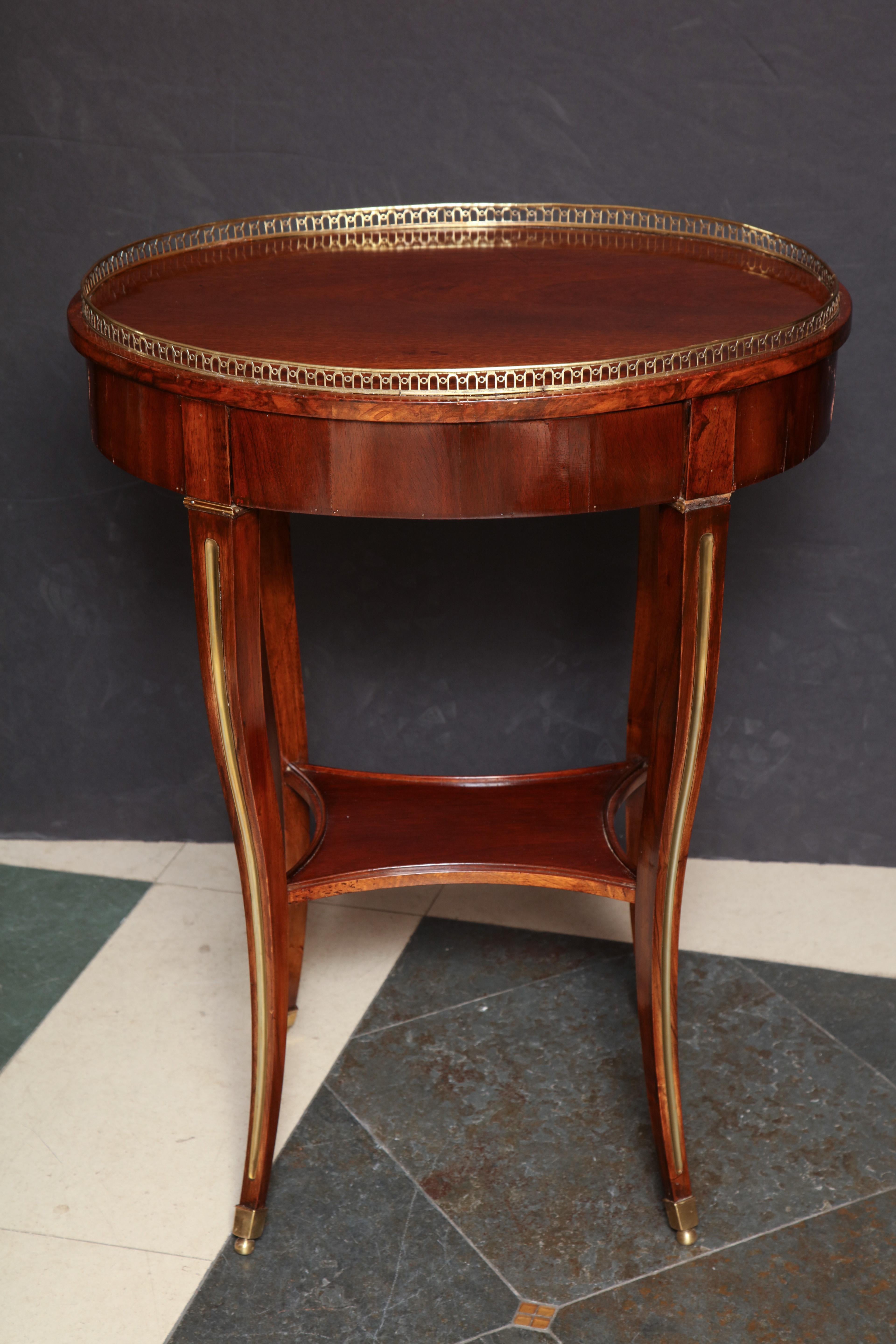 A fine Russian neoclassic oval mahogany side table with a pierced bronze gallery, brass fluted sweeping legs, and shelf stretcher base. Having a single drawer and bronze feet.