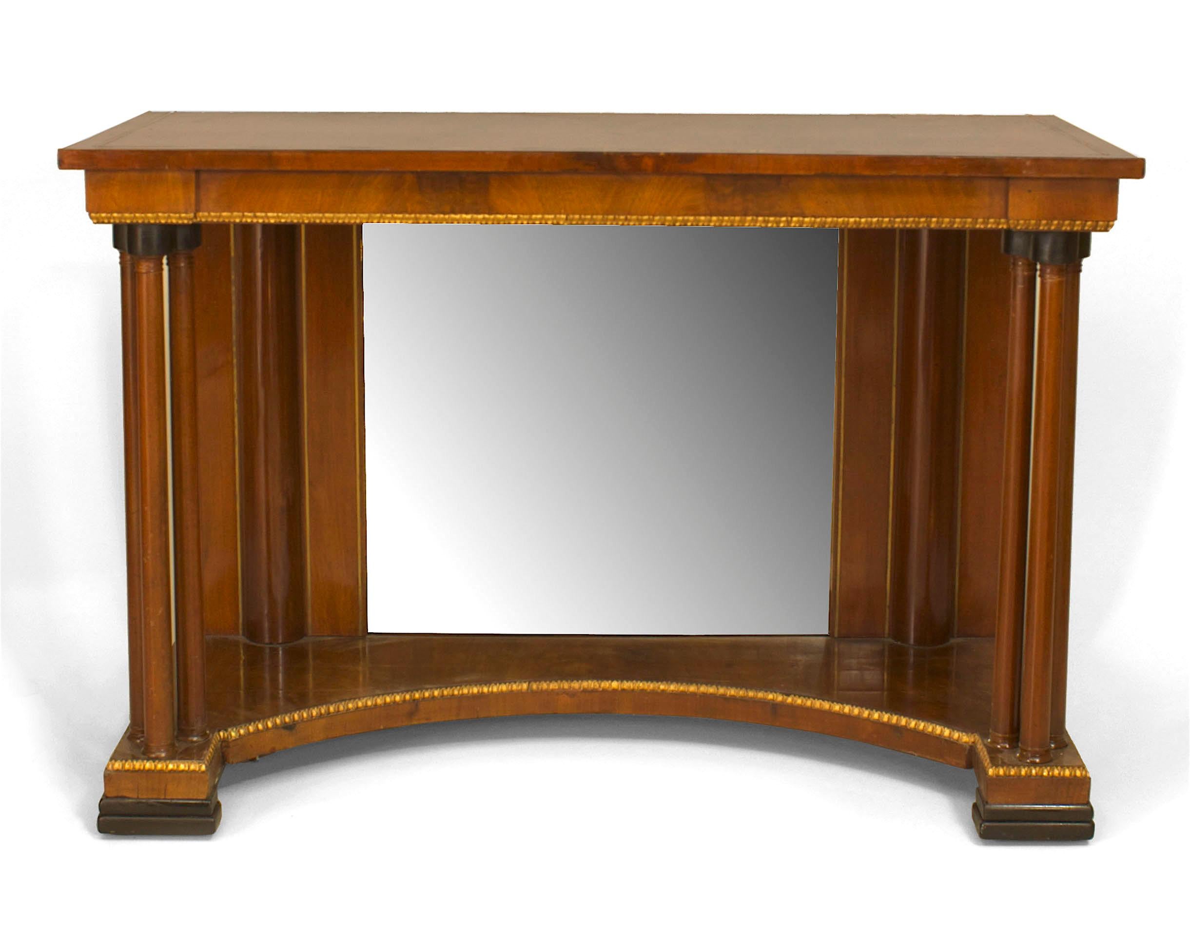 Russian neoclassic style mahogany and brass banded inlaid top console table with parcel gilt and ebonized trim having three columns over a concave fronted base and a mirror backing (19th century).
 