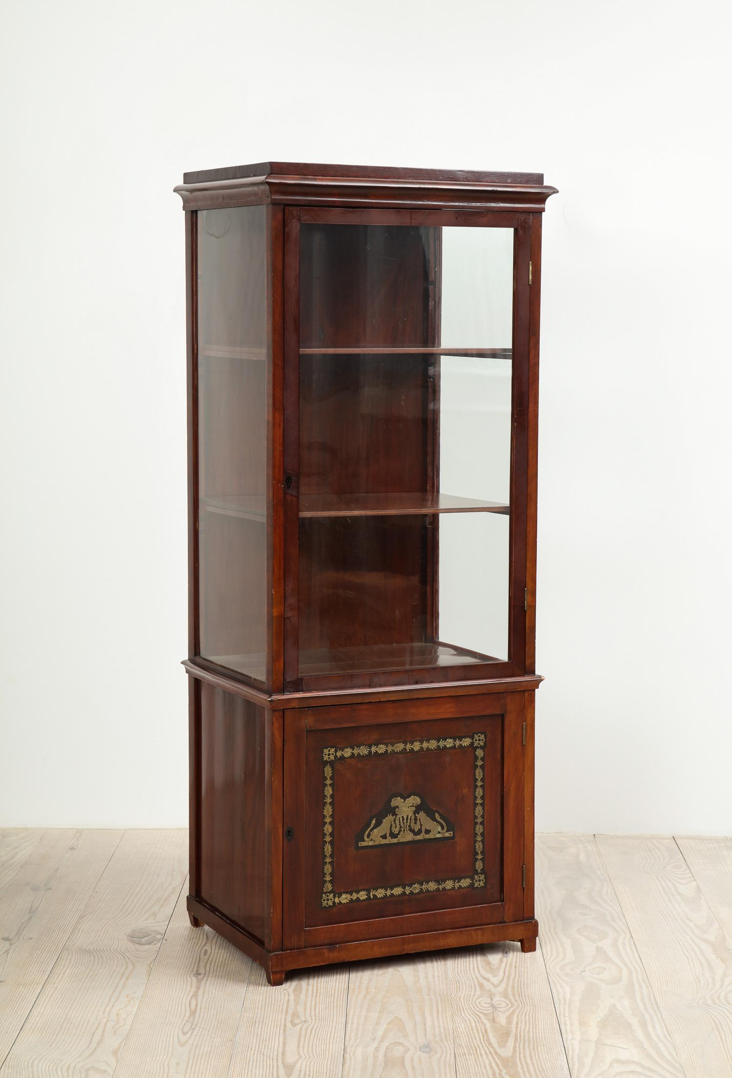 Russian neoclassical mahogany cabinet with brass inlay, circa 1820.

Upper cabinet fitted with glass sides and front glass door with three shelves; bottom section single door cabinet.
 