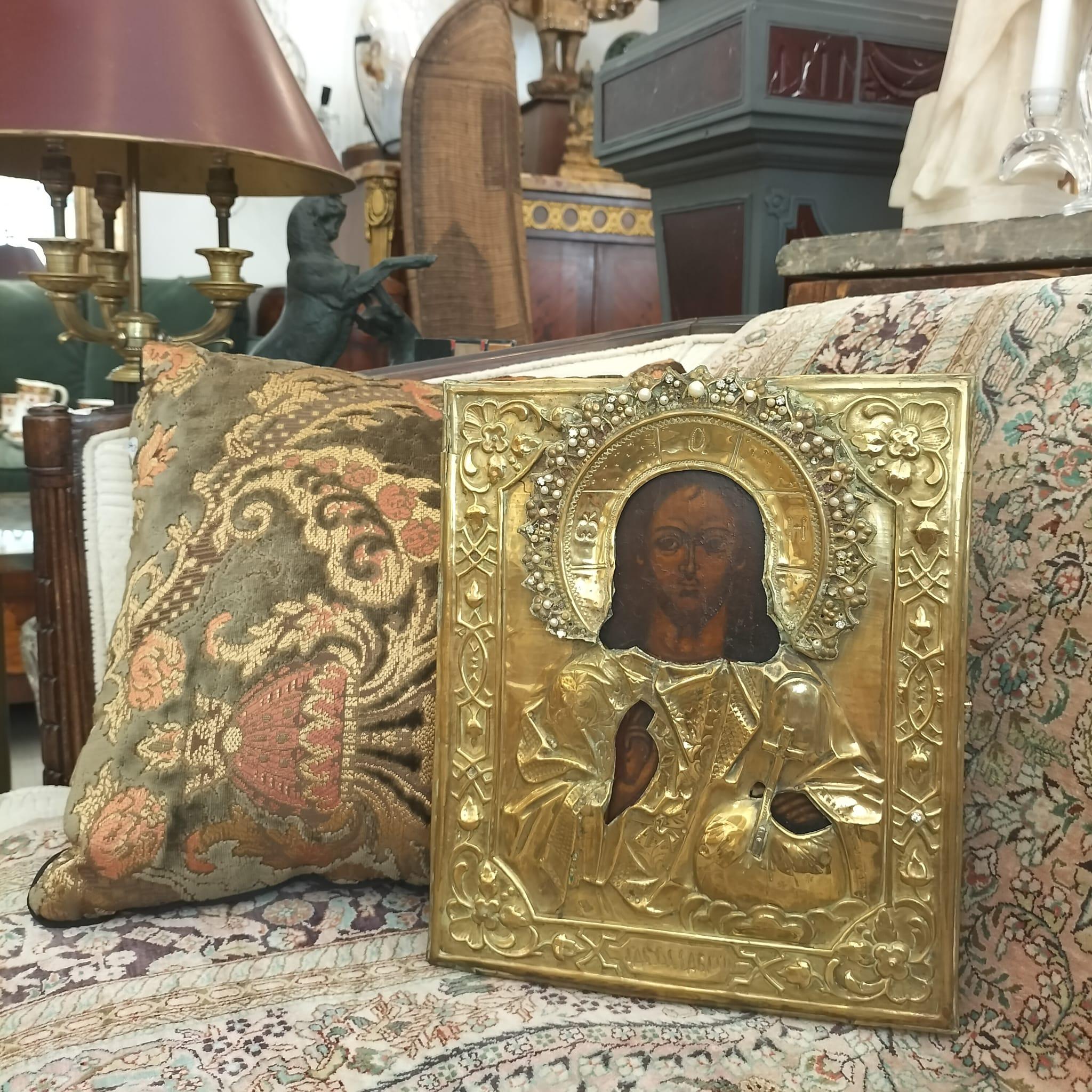 Questa icona ortodossa russa del XIX secolo raffigura Cristo. Il volto di Cristo è incastonato all'interno di una riza d'oro intricata e contiene dettagliati motivi floreali e geometrici. Il contrasto tra il volto dipinto di scuro e lo sfondo dorato