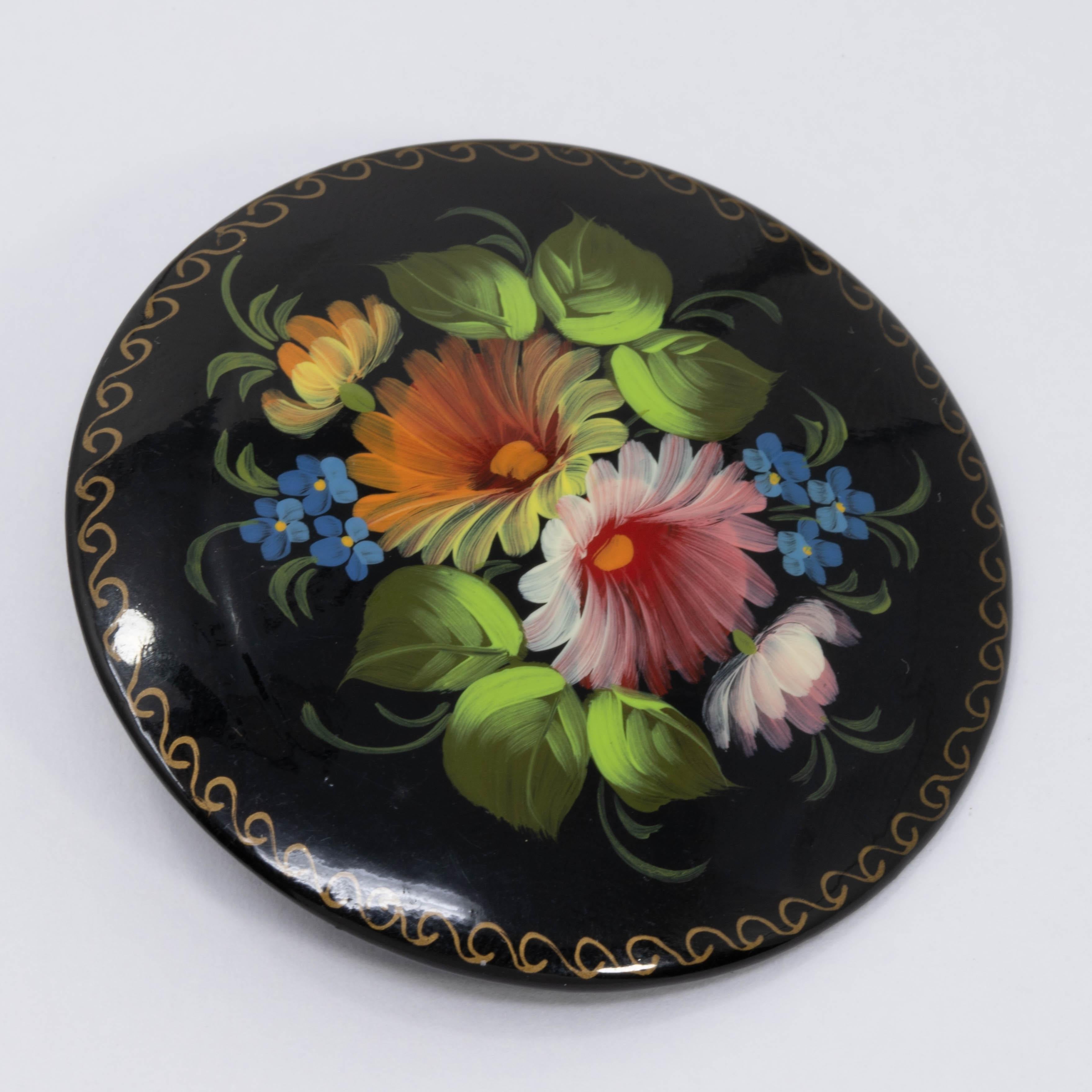 A masterfully painted wooden vintage Russian Lacquered pin featuring a colorful bouquet of flowers, with a golden-accent border.

Hand signed in Cyrillic on the back