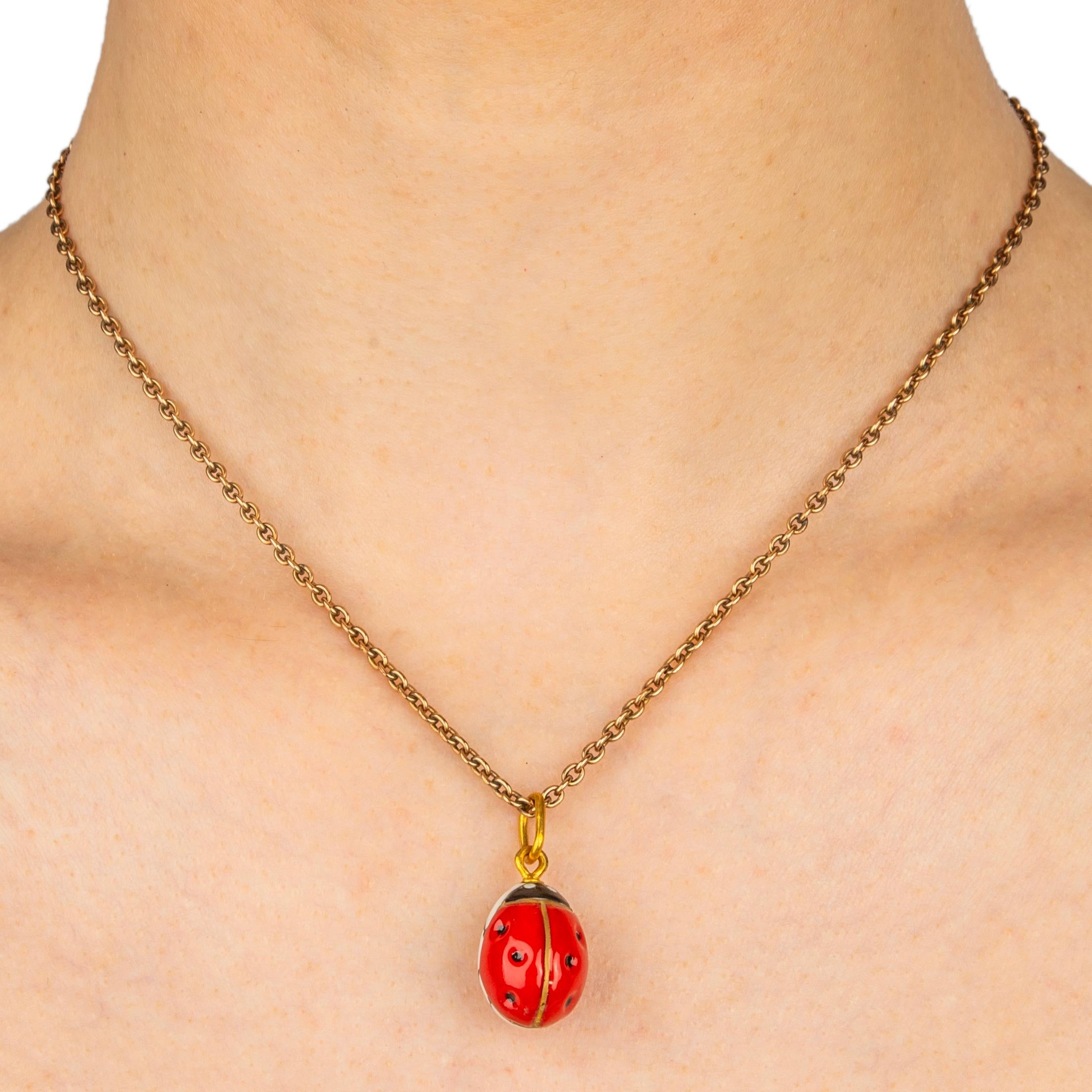 A beautiful porcelain miniature egg pendant, the front featuring a slightly domed bright red lady bug, the reverse detailing its black legs on a white opalescent ground. Fitted with a large oval gilded suspension ring to accommodate different size