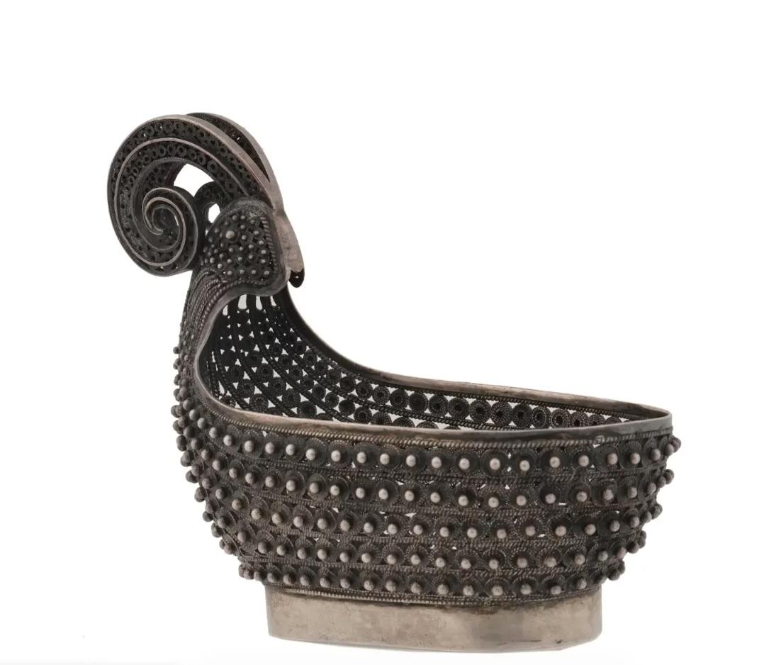 A Russian silver kovsh decorated throughout the body with pointed scrolling filigree patterns and a curved horn-like handle. Stands on an oval base. Hallmarked with the manufacturer mark. Total weight: 158 grams. Russian Silverware