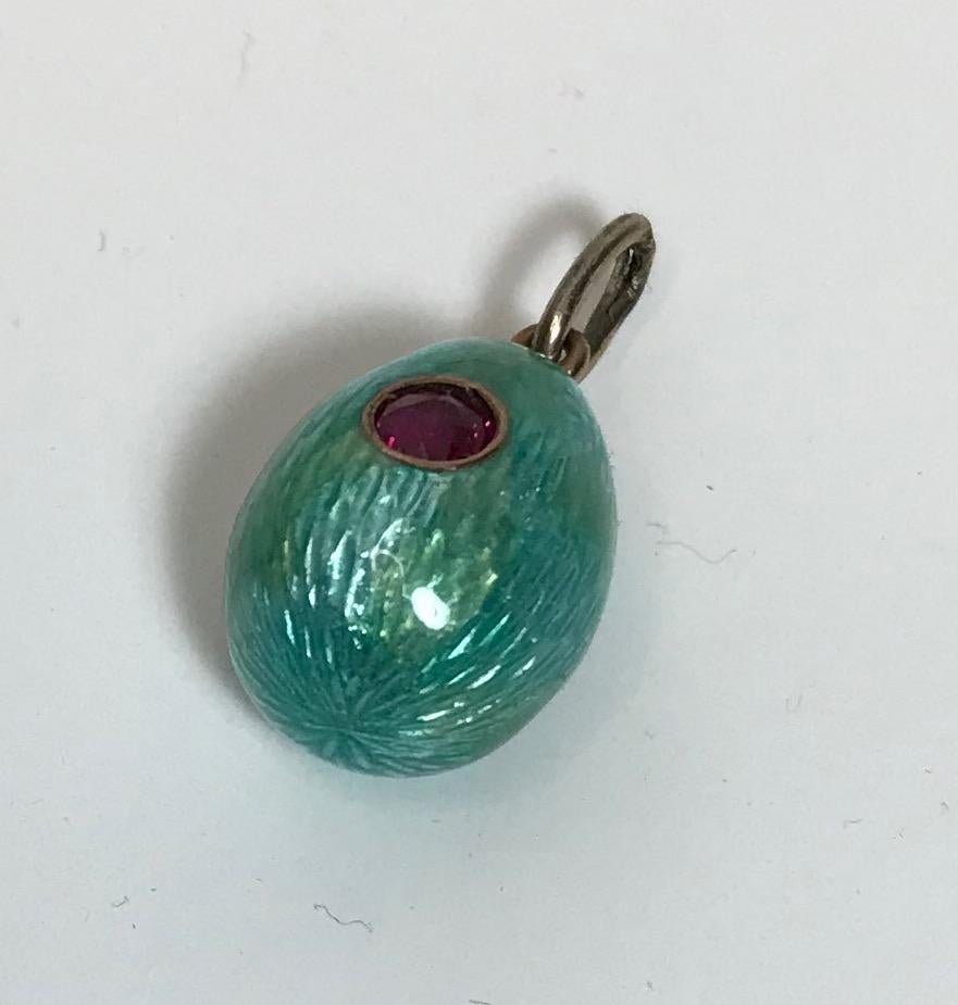 From the Romanov era, period of Tsar Nicholas II, a rare Russian teal blue guilloché enameled miniature egg pendant (enamel repaired) enhanced with a circular-cut ruby bead set in a silver bezel, fitted with a gold suspension ring. 

circa 1900

7/8