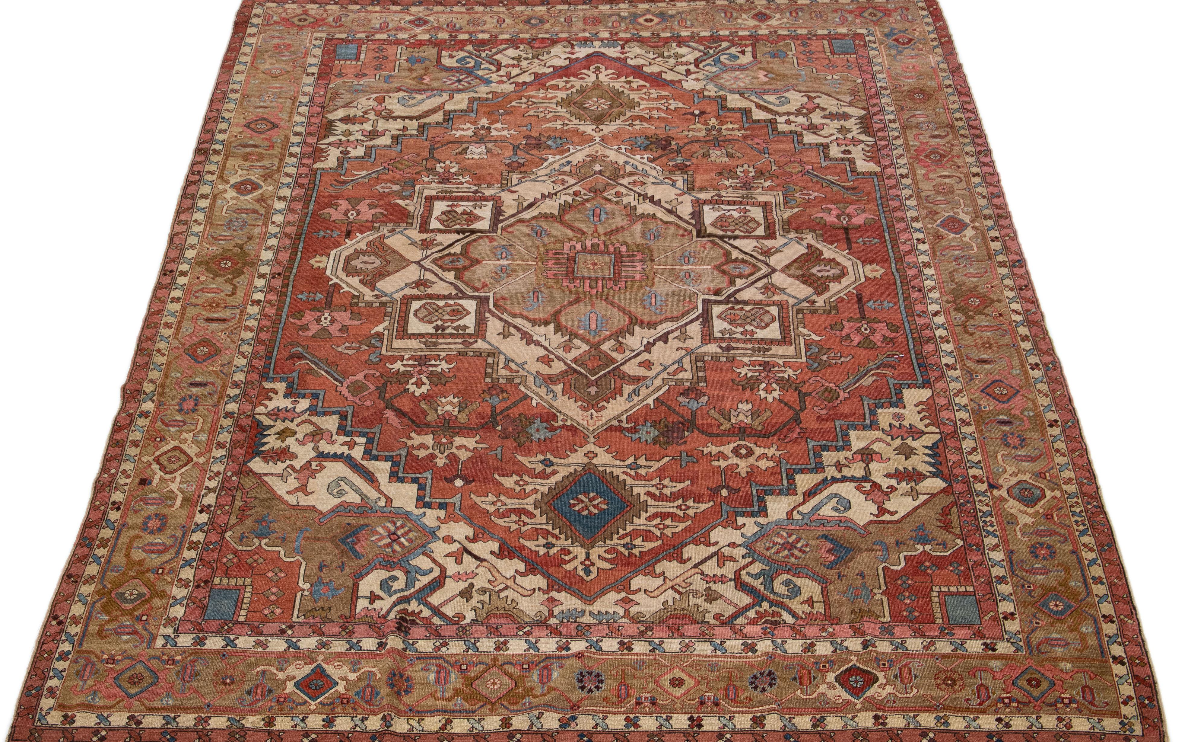Beautiful antique serapi hand knotted wool rug with a rust color field. This Persian rug has a brown designed frame with multicolor accents in a gorgeous medallion floral motif. This stunning handcrafted work of art will add warmth and