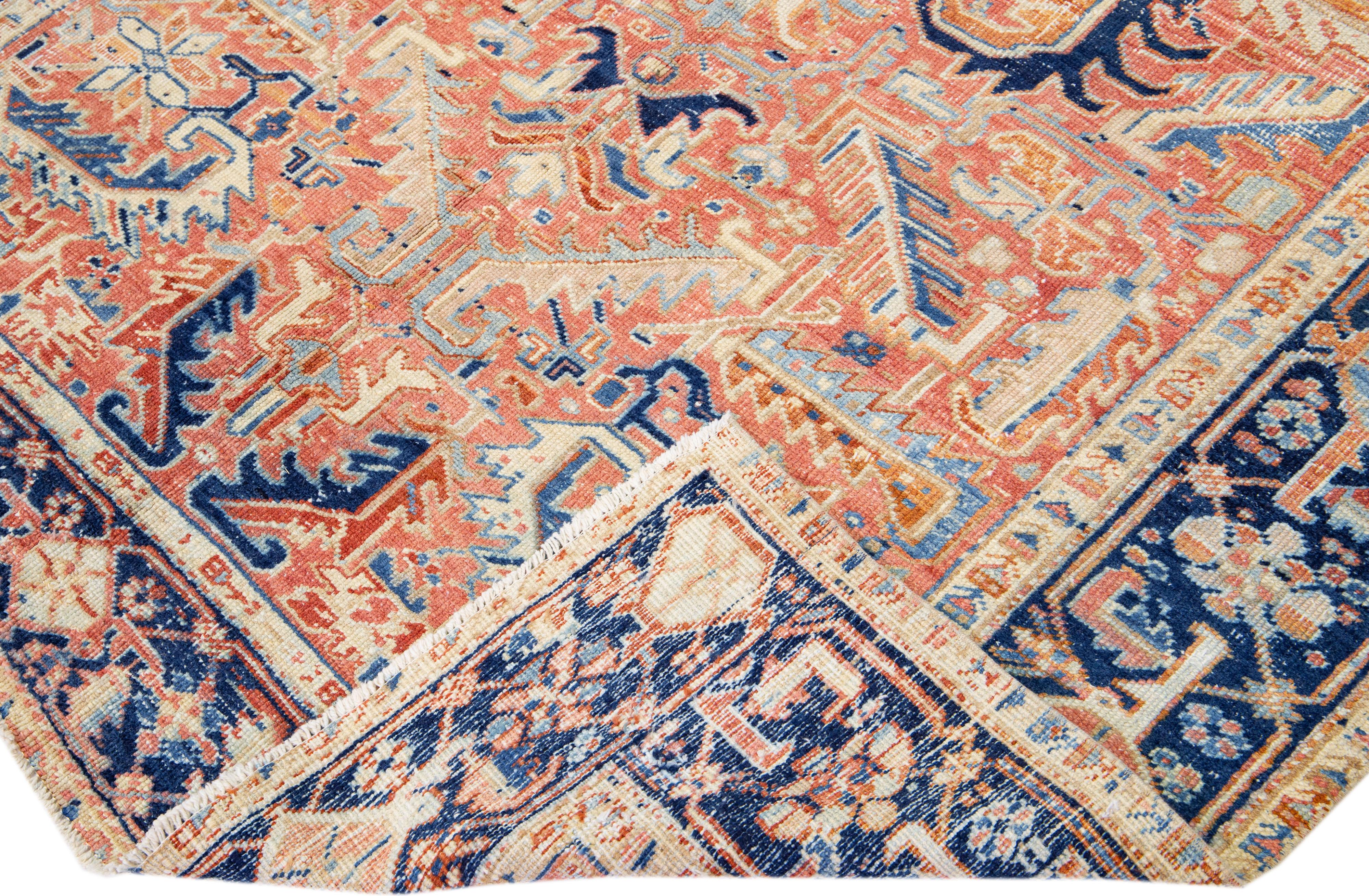 Beautiful antique Heriz hand-knotted wool rug with a rust color field. This Persian rug has a blue frame with orange and beige accents in a gorgeous all-over geometric floral design.

This rug measures: 6'8