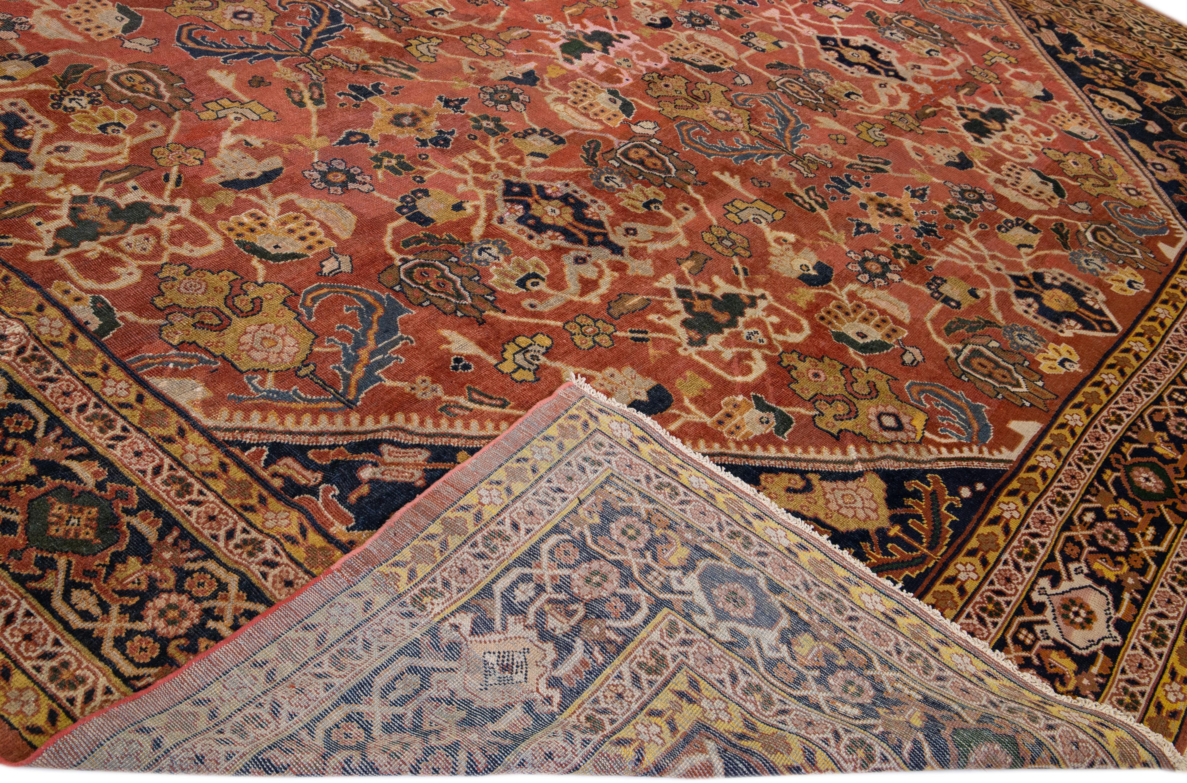 A beautiful Antique Mahal hand-knotted wool rug with a rust color field. This rug has a dark blue frame and multicolor accents in an all-over floral design.

This rug measures 15'6