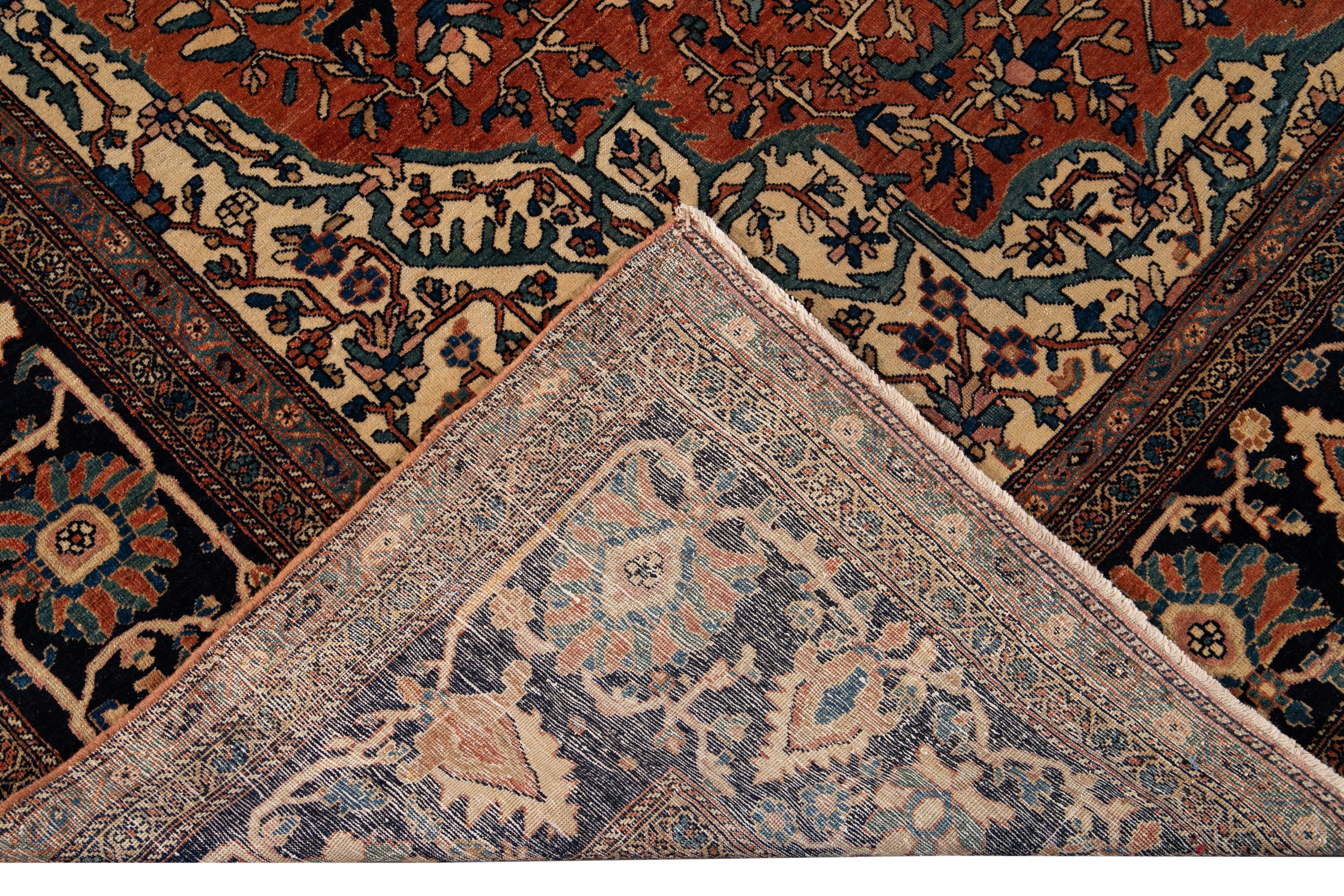 Beautiful Antique Farahan hand-knotted wool rug with an orange-rust color field. This Persian rug has a designed dark blue frame with multicolor accents on a Classic floral medallion design.

This rug measure: 9' x 12'8