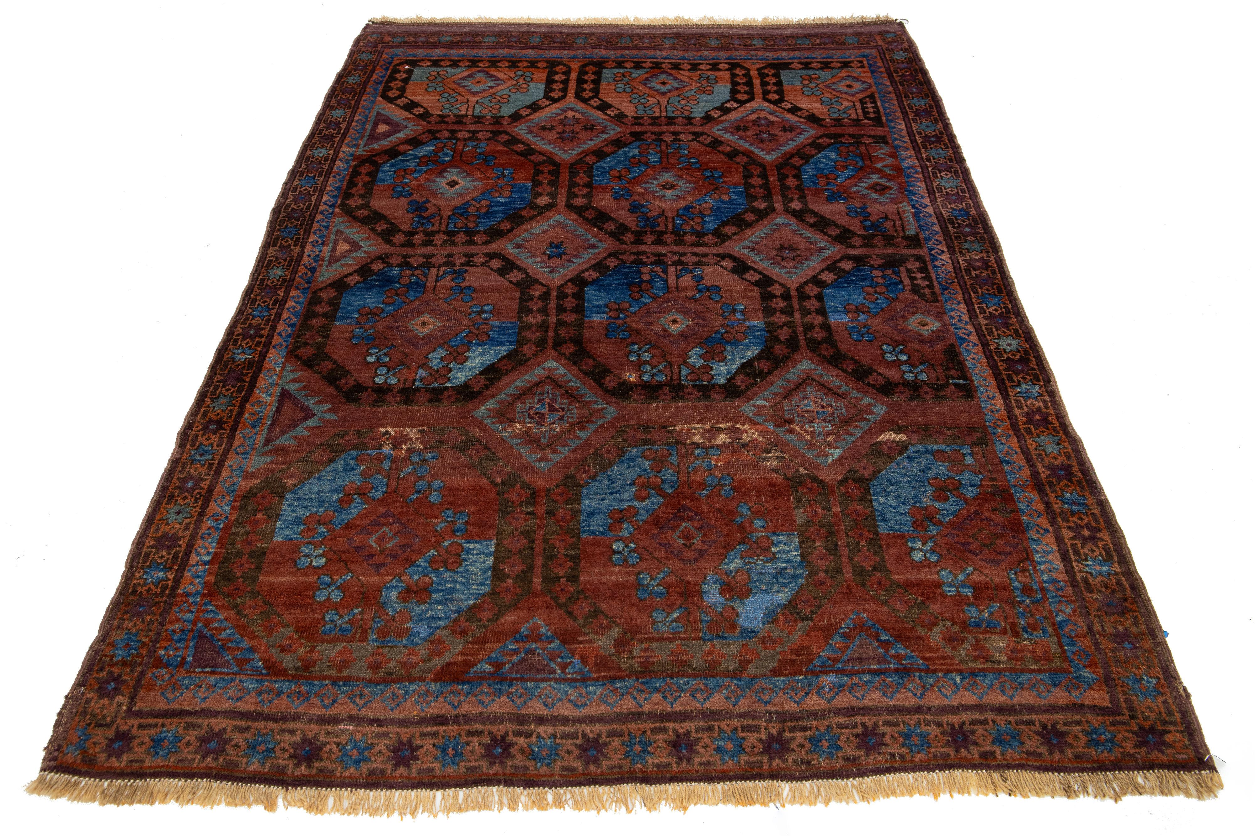 Antique hand-knotted wool rug from Turkmen with a rust field. This Persian rug features blue and terracotta accents with fringes in an intricate geometric pattern.

This rug measures 5'2'' x 7'5''.


