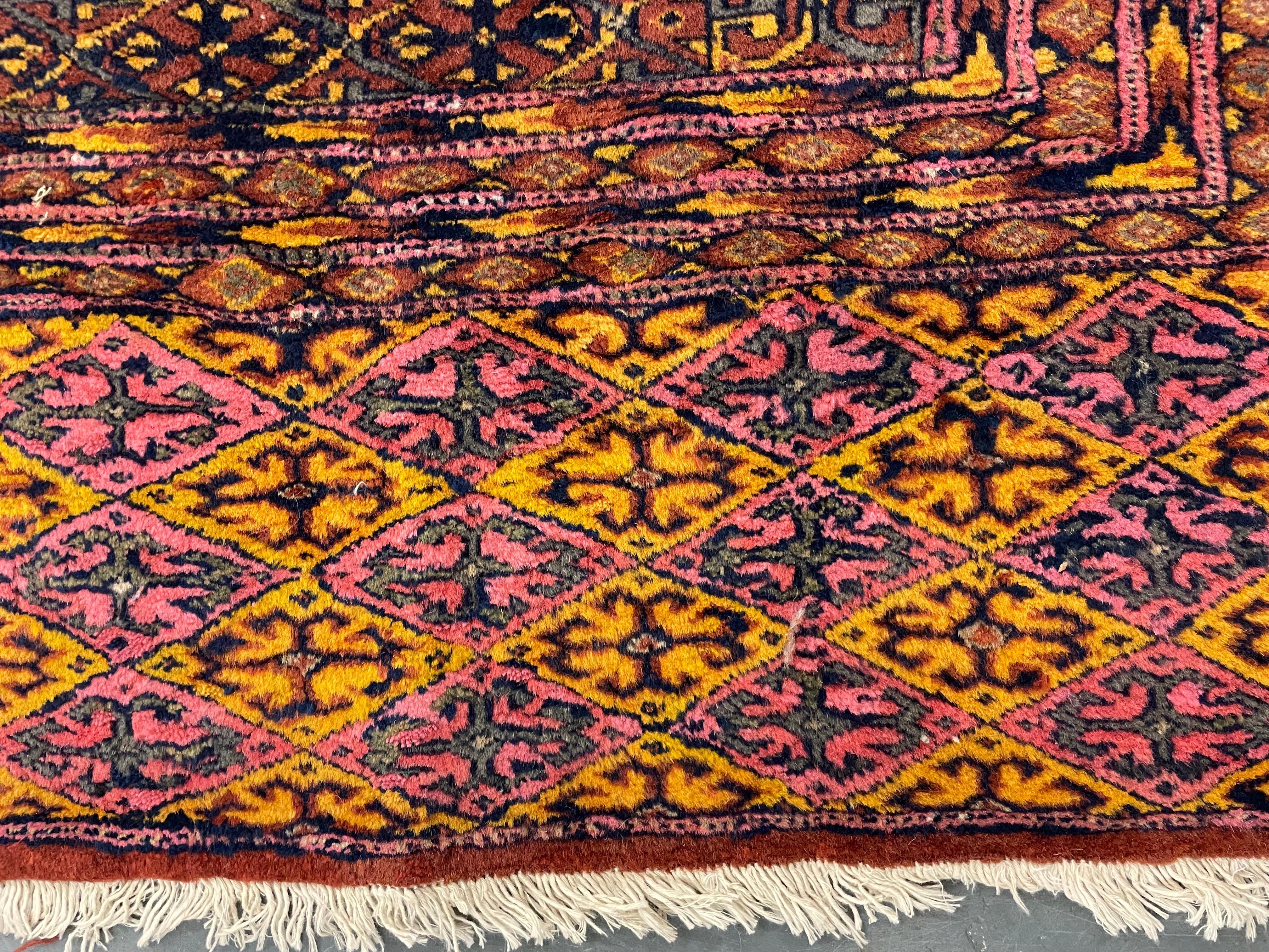 This elegant traditional Bukhara carpet area rug was woven by hand in the 1930s. The main design features repeat pattern which is created by large scale geometric patterns, woven in deep rust background with green and hint of rich red near border.
