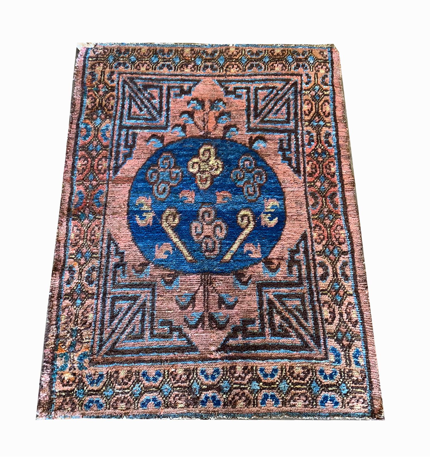 This unique small Kohtan carpet was woven by hand in the 1900s. Khotan rugs were created in East Turkestan in an area that is now Western China. Khotan was once a desert oasis on the silk road and produced bold rugs known for their circular