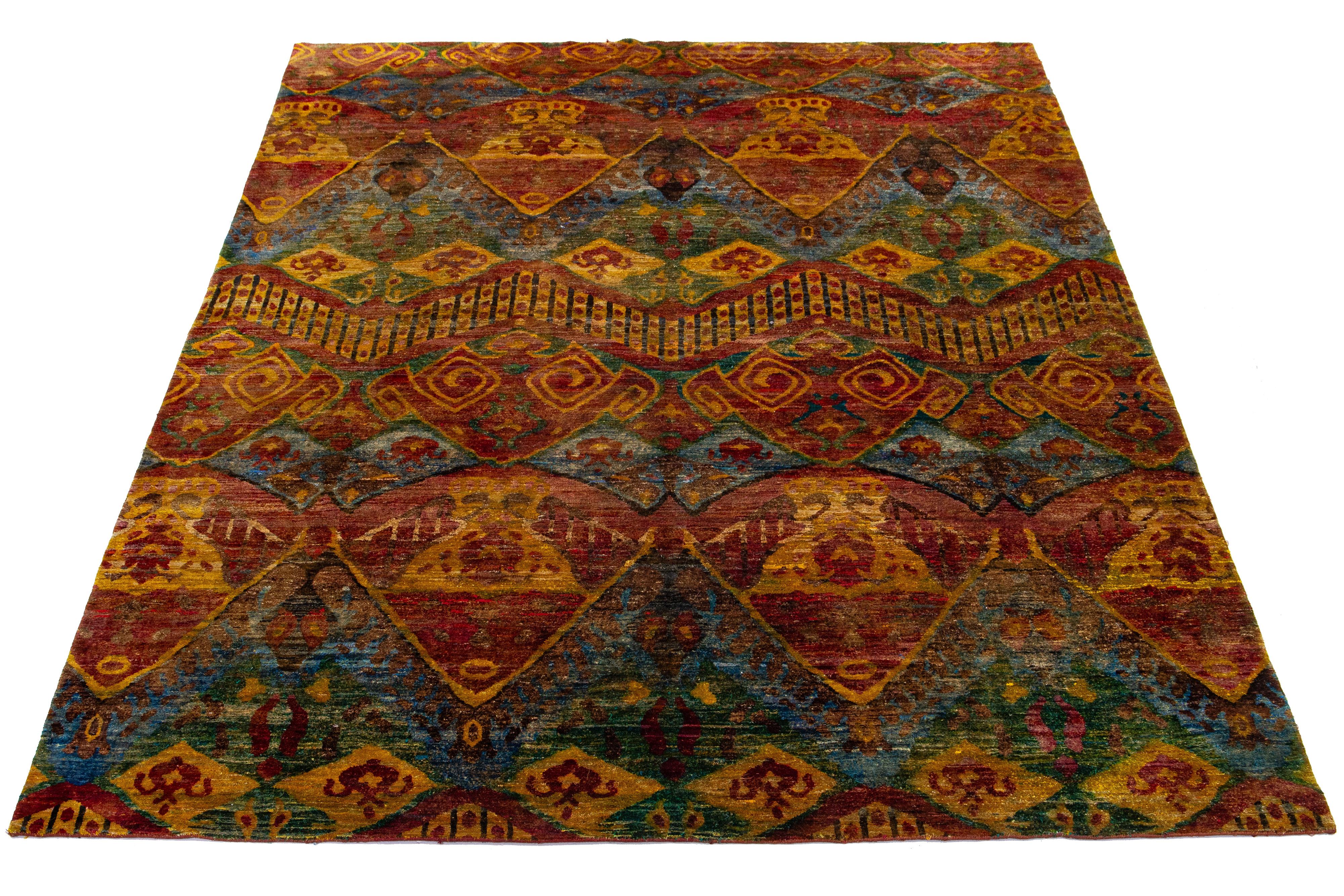 Dieser handgeknüpfte Teppich aus Wolle und Sari-Seide im Bidjar-Stil zeigt ein rostfarbenes Feld. Es ist mit einem atemberaubenden geometrischen Muster gestaltet und wird durch goldene, blaue, grüne und braune Farbtöne akzentuiert, die ihm einen