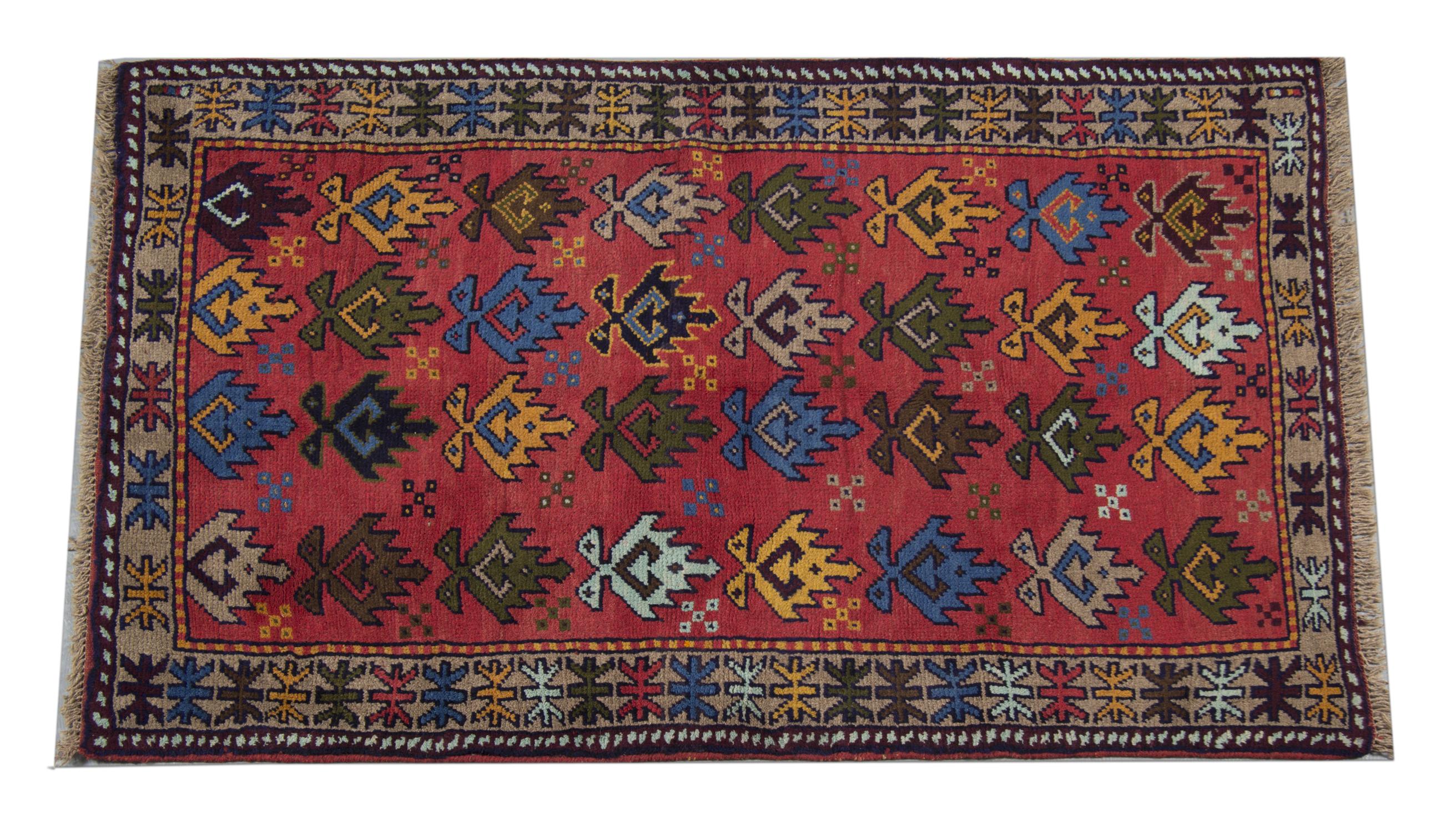 This elegant floral carpet was woven by hand in the 1990s. The central design has been woven on a rich red background with geometric motifs in green, yellow, and blue accents. Both the colour and design in this piece make it the perfect accent rug.