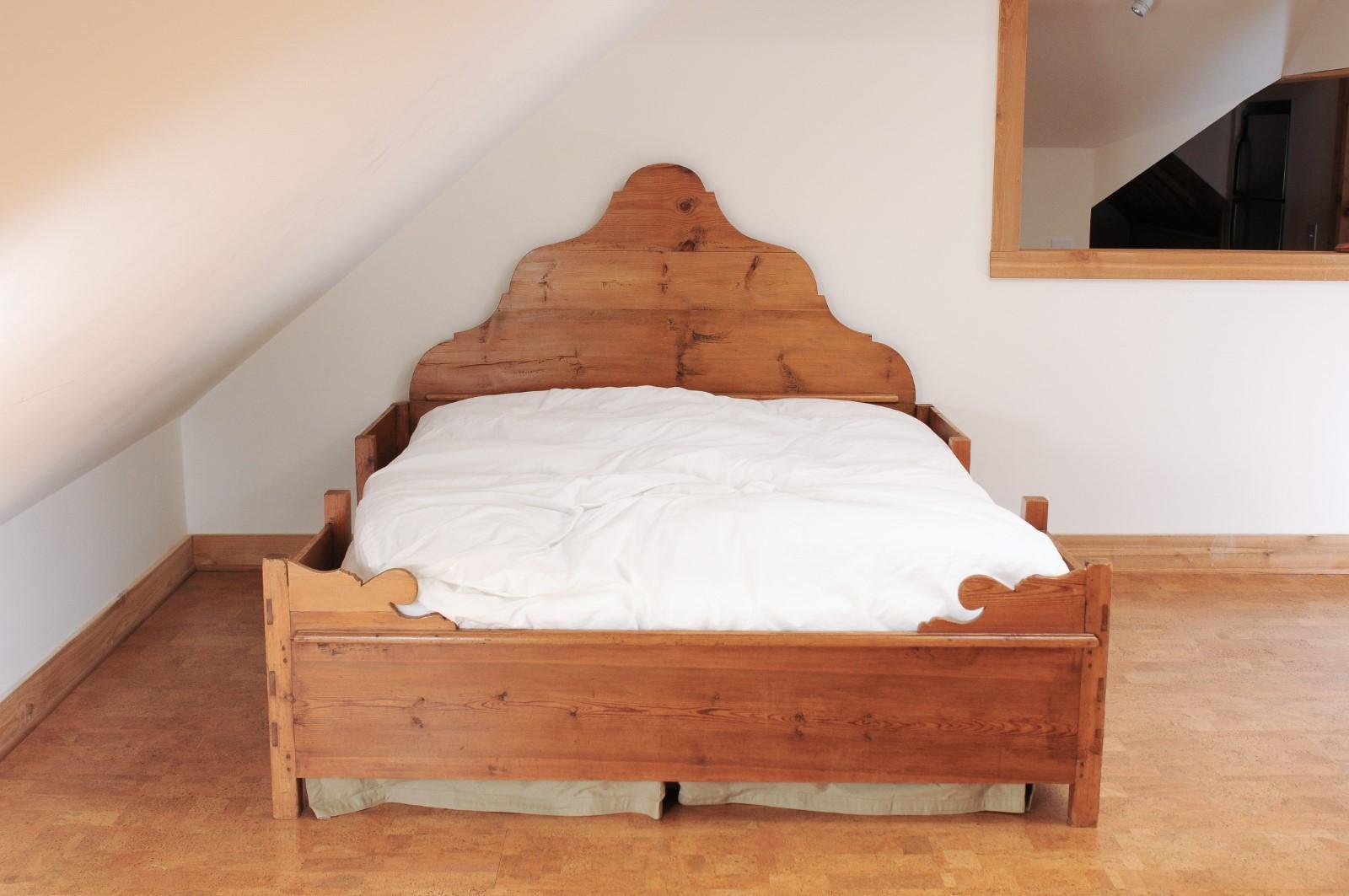 A rustic Scandinavian fir bed from the mid-19th century, with tall scrolling headboard, custom mattress and box spring. Created in Sweden during the second quarter of the 19th century, this fir bed attracts our attention with its rustic appearance