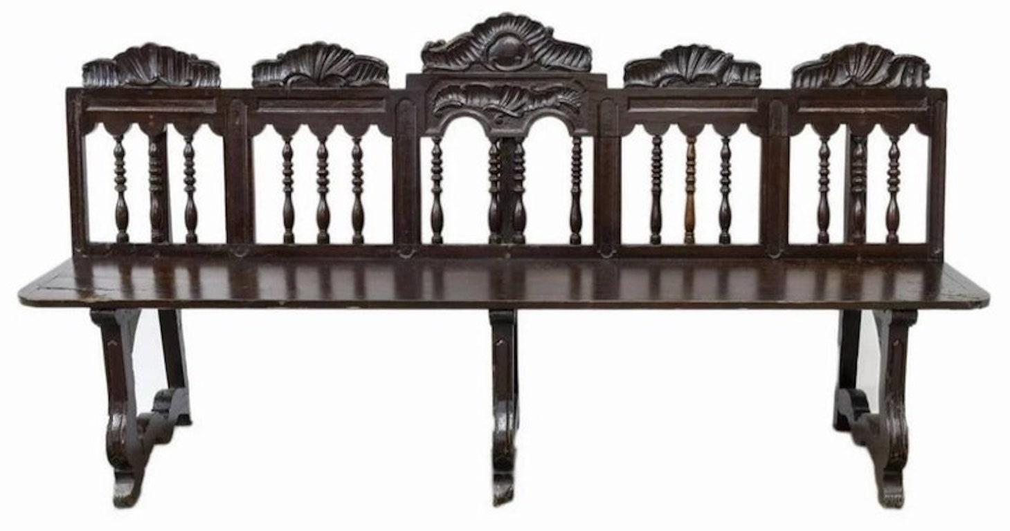 An extremely rare, rustic, hand carved walnut Spanish seven foot long bench with outstanding patina. Crafted during the eighteenth century Colonial period, featuring a shaped back rail with well carved ornamentation, over a gallery of hand-turned