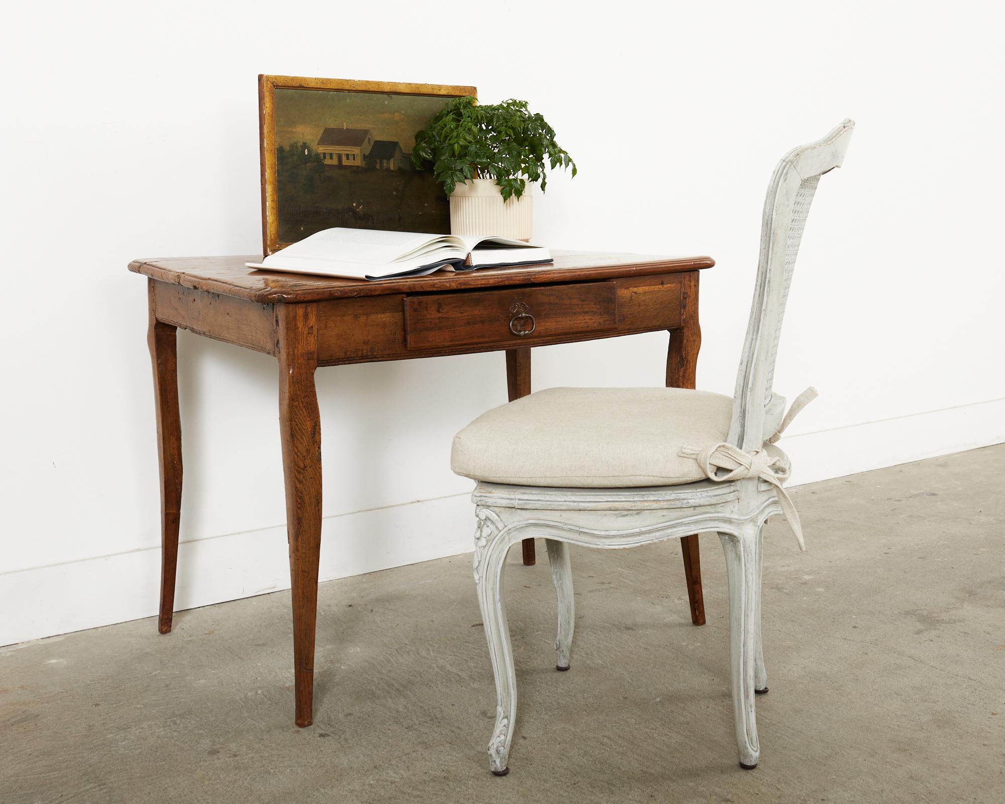 Charmanter und rustikaler Schreibtisch aus dem späten 18. Jahrhundert, handgefertigt aus Obstholz. Dieser in Südfrankreich hergestellte Tisch hat einen skurrilen, charaktervollen Stil mit einer unebenen Platte und einer stark abgenutzten Patina. Der