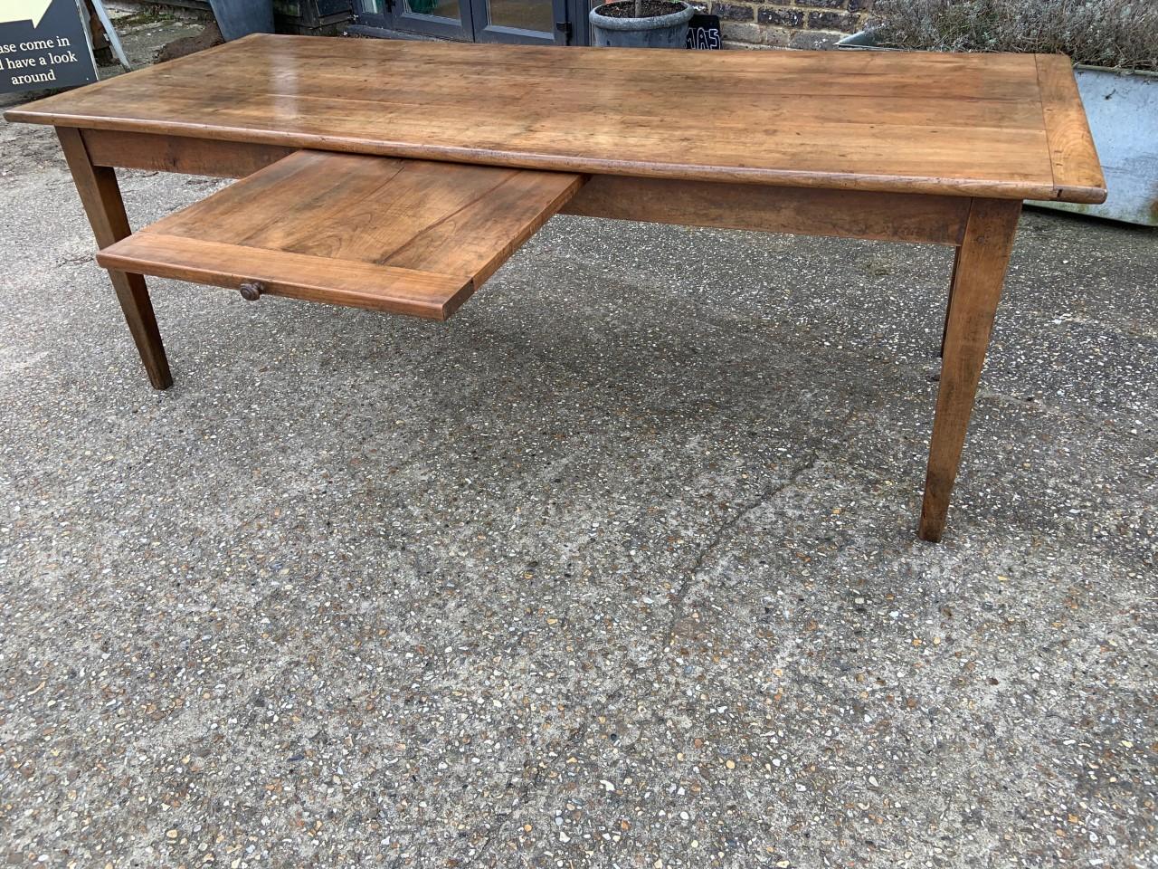 Rustic antique cherry farmhouse table with slide and tapered legs. 19th century farmhouse table with gorgeous patination and color. Table has little bread slide on one side.
          