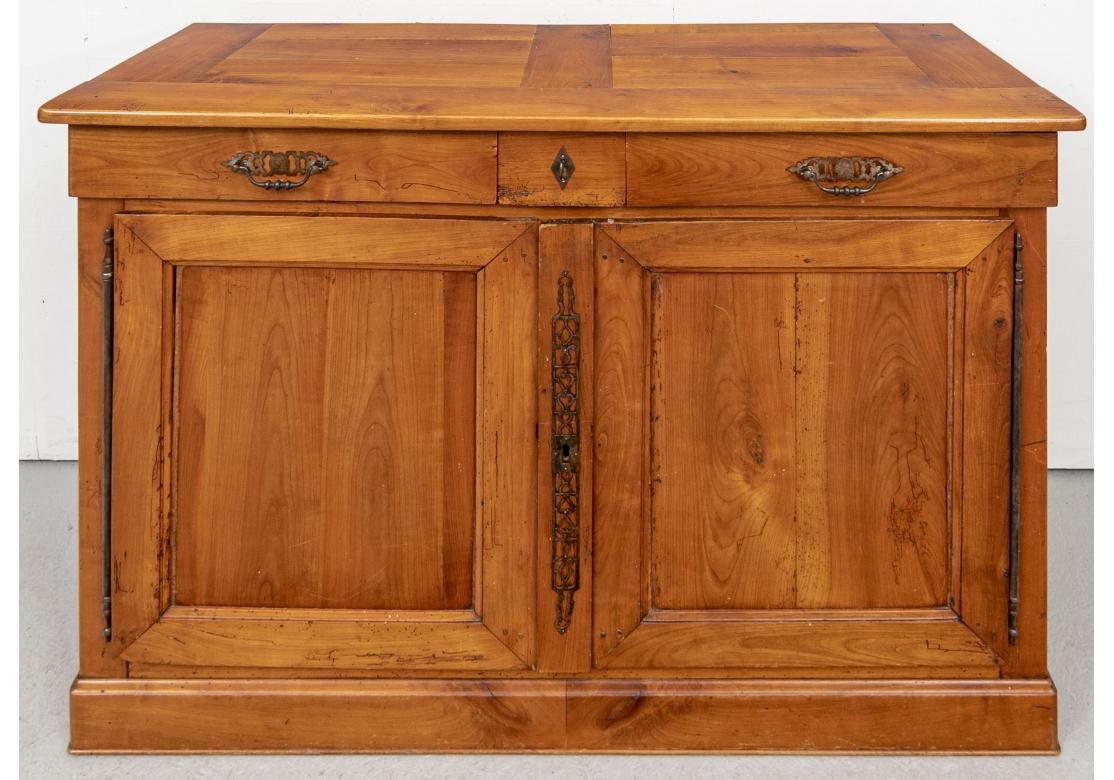 A authentic serving cabinet with good color and great Rustic form. With a banded plank made top. The frieze with two long drawers with metal bales flanking the small center drawer with key form pull on the faux escutcheon. Double doors with recessed