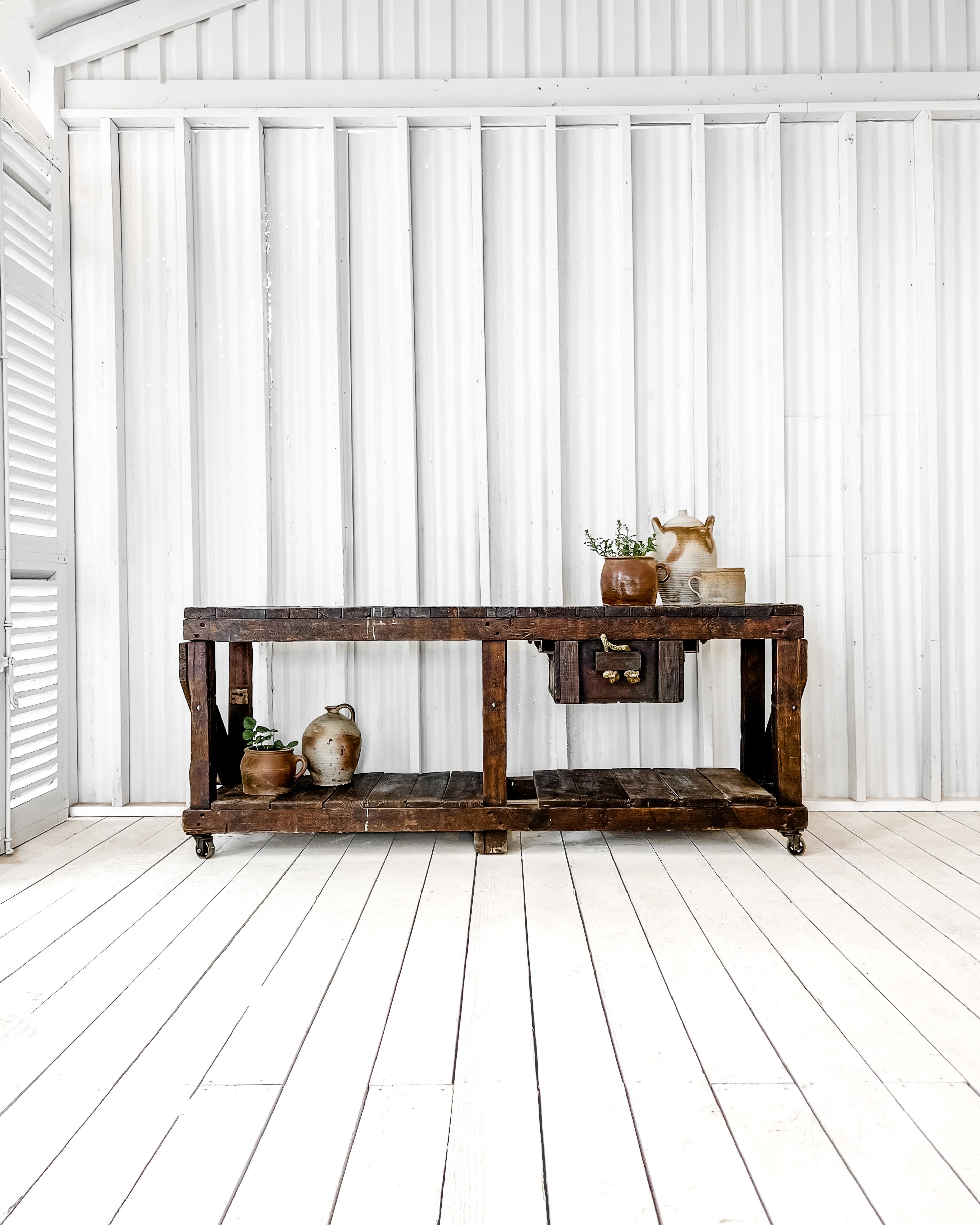 Primitive in design, yet built to last, this solid oak planked workbench, with its dark stain and industrial iron casters, is the perfect piece to mix with modern furnishings, adding a layer of character and authenticity to a modern home. The tongue