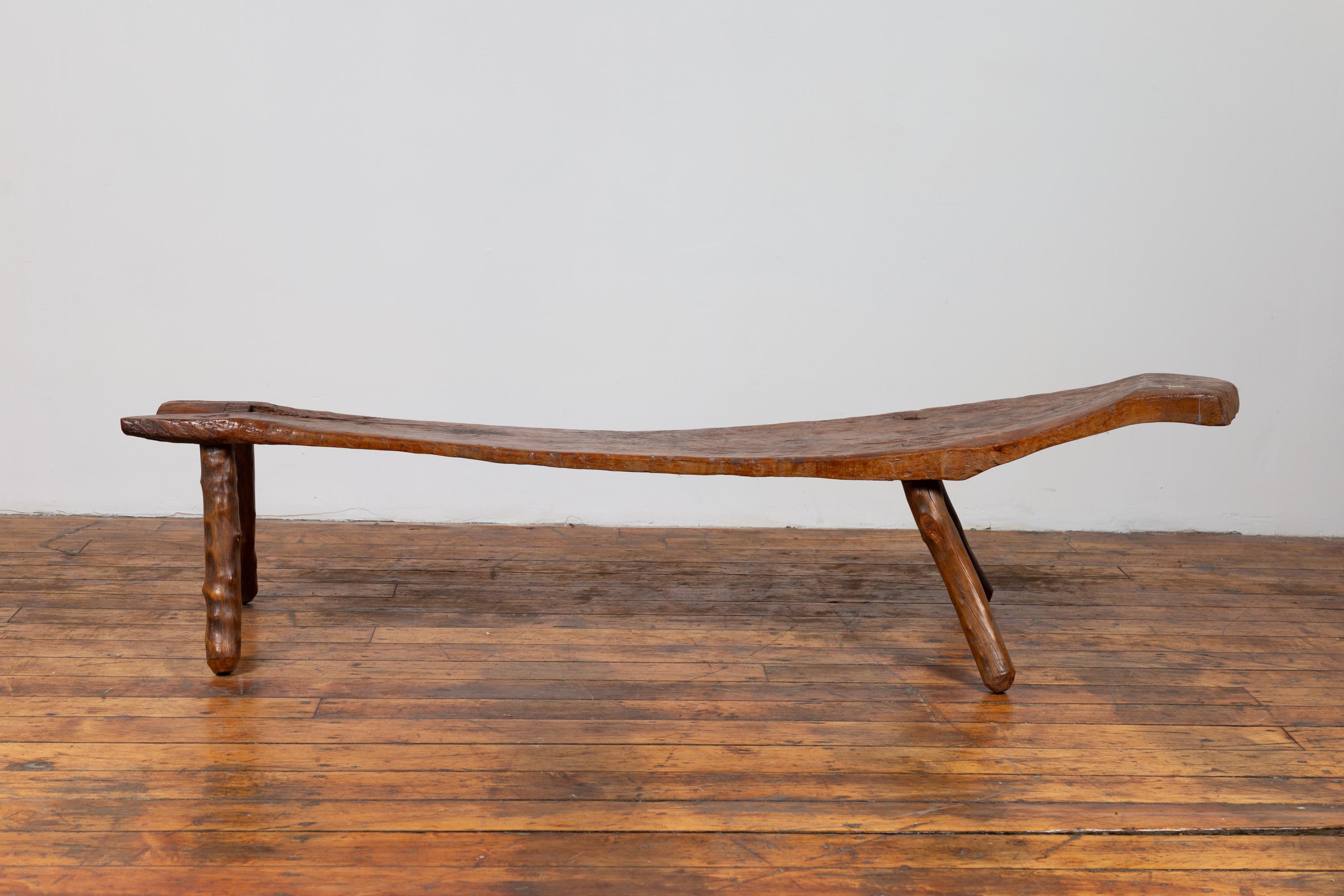 A rustic Indonesian freeform wooden bench from the 19th century, with weathered appearance. Born on the Island of Java during the 19th century, this rustic wooden bench charms our eyes with its freeform Silhouette and nicely weathered patina. A long