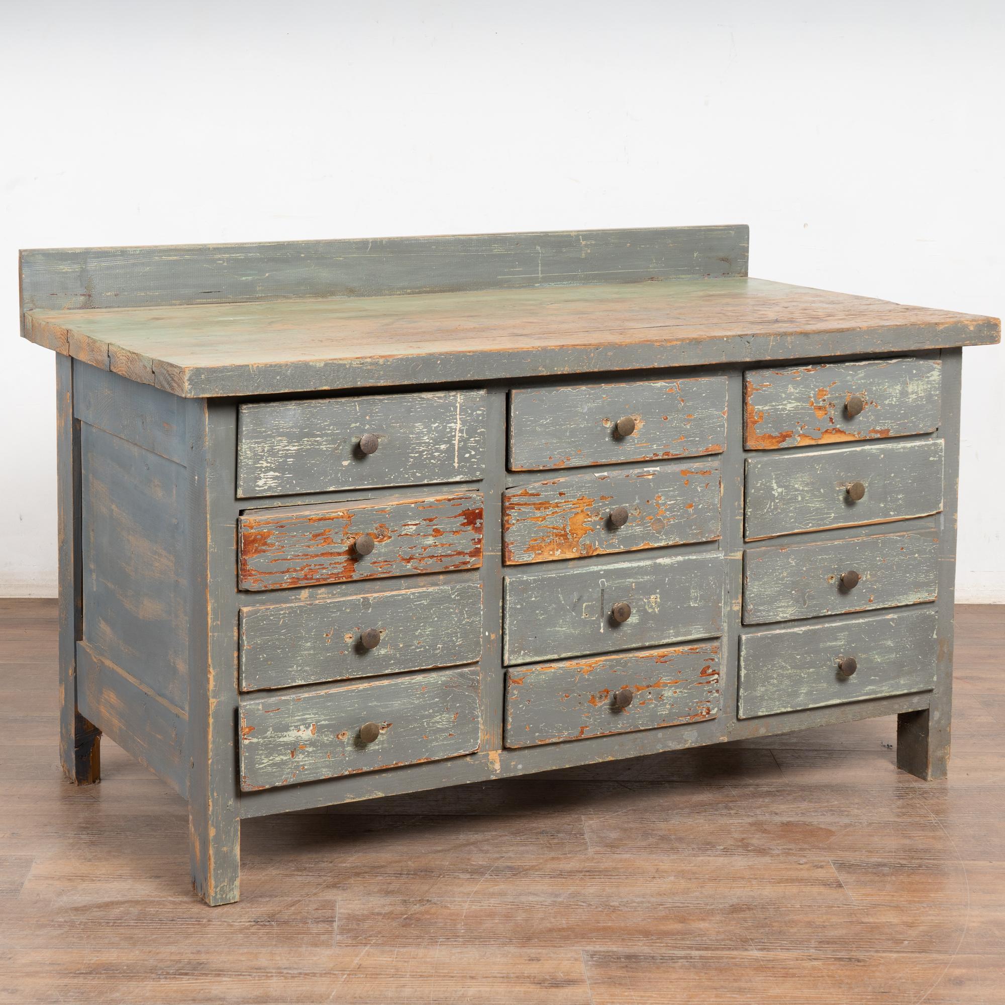 Questa spezieria a 12 cassetti in legno di pino è stata probabilmente utilizzata come bancone di un negozio o in un'officina tra la fine del 1800 e i primi anni del 1900.
Gli strati di vernice originale rivelano tocchi di bianco, uno strato di verde