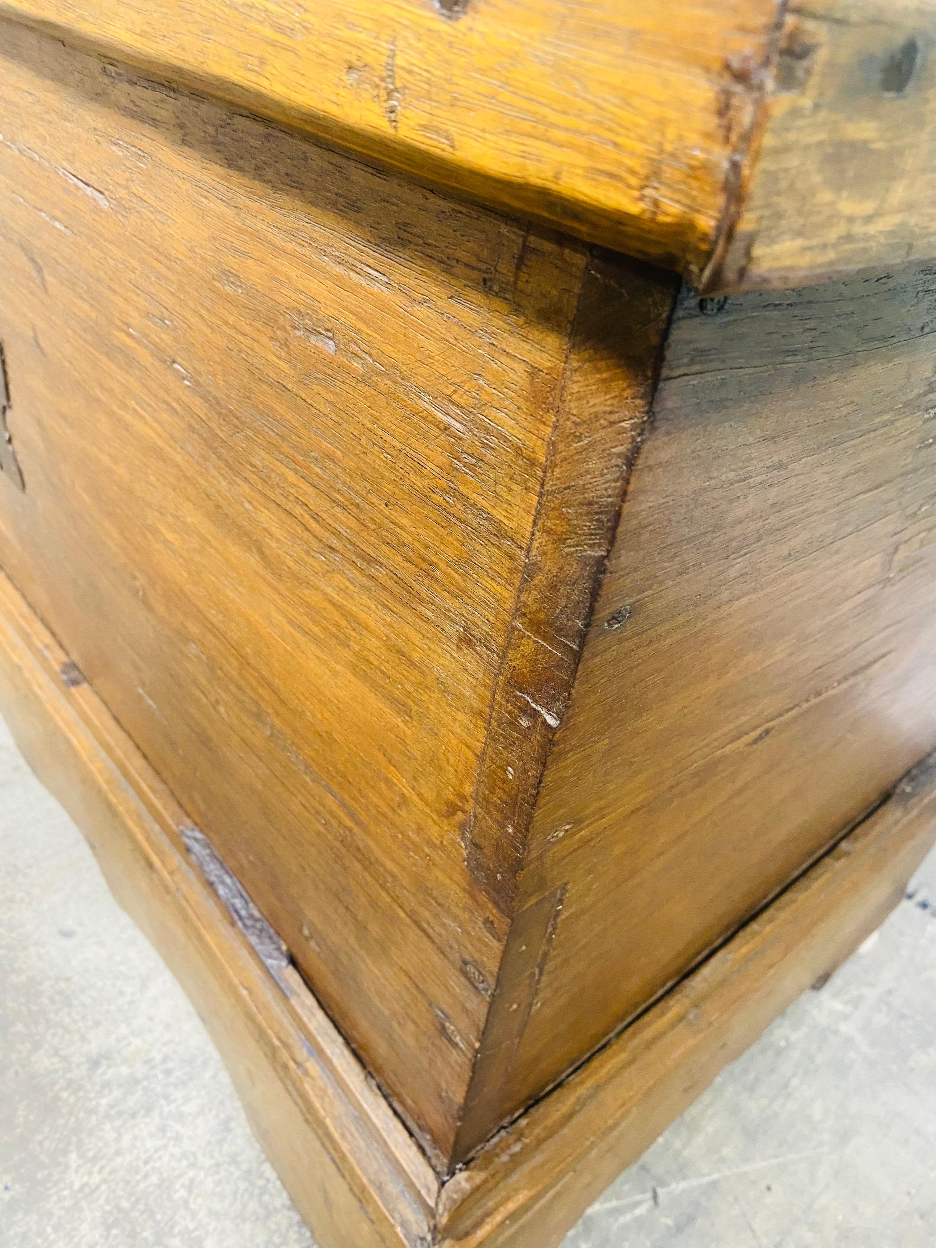 This is a 19th century handmade rustic chest. This chest has hand forged iron hinges on the top with a hand forged iron locking mechanism on the front. The chest has a scrolled apron base with large dovetails on the corners. This chest was American