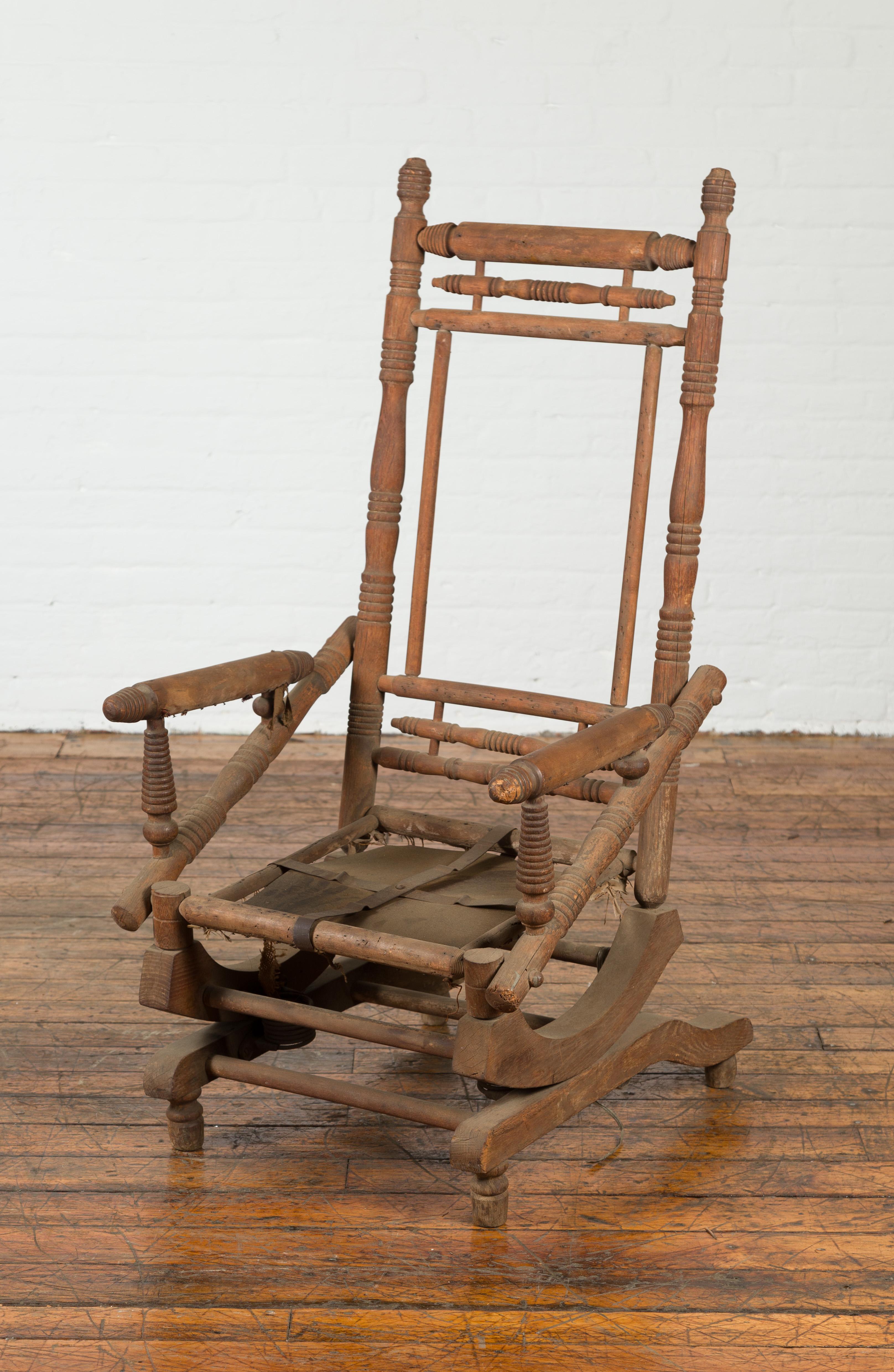 A rustic antique Indian rocking chair from the 19th century, with metal accents and nicely distressed appearance. Created in India during the 19th century, this rocking chair charms us with its highly distressed appearance and great age. Showcasing