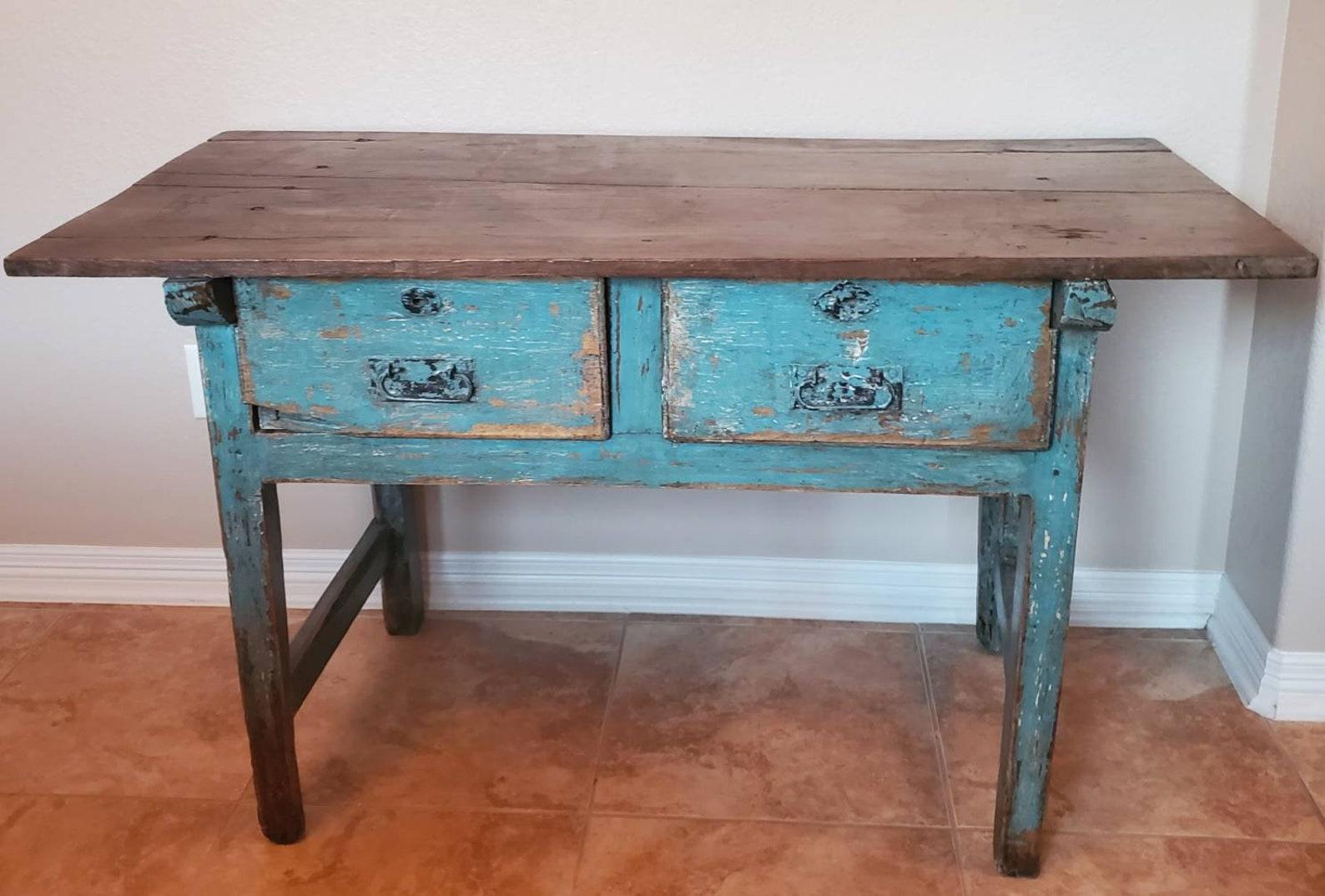 Patina perfection!! A rustic 19th century hand-crafted Spanish work table, in a distressed, weathered painted finish. Having a rectangular two board wooden plank top with beautiful, rich patina, over solid pine case fitted with two large hand carved