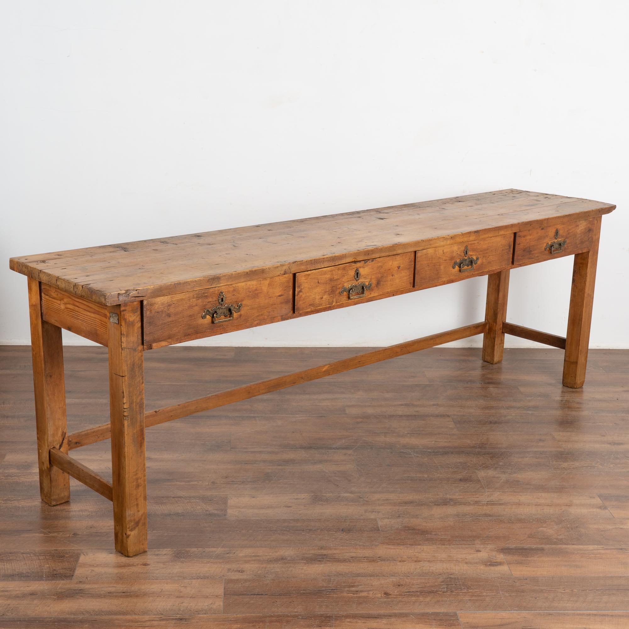This long rustic console is a great find not only due to its 8' length, but with the four drawers that add function as well.
Originally used as a type of work table, it is the generations of use revealed in every nick, gouge, stain, hole and crack