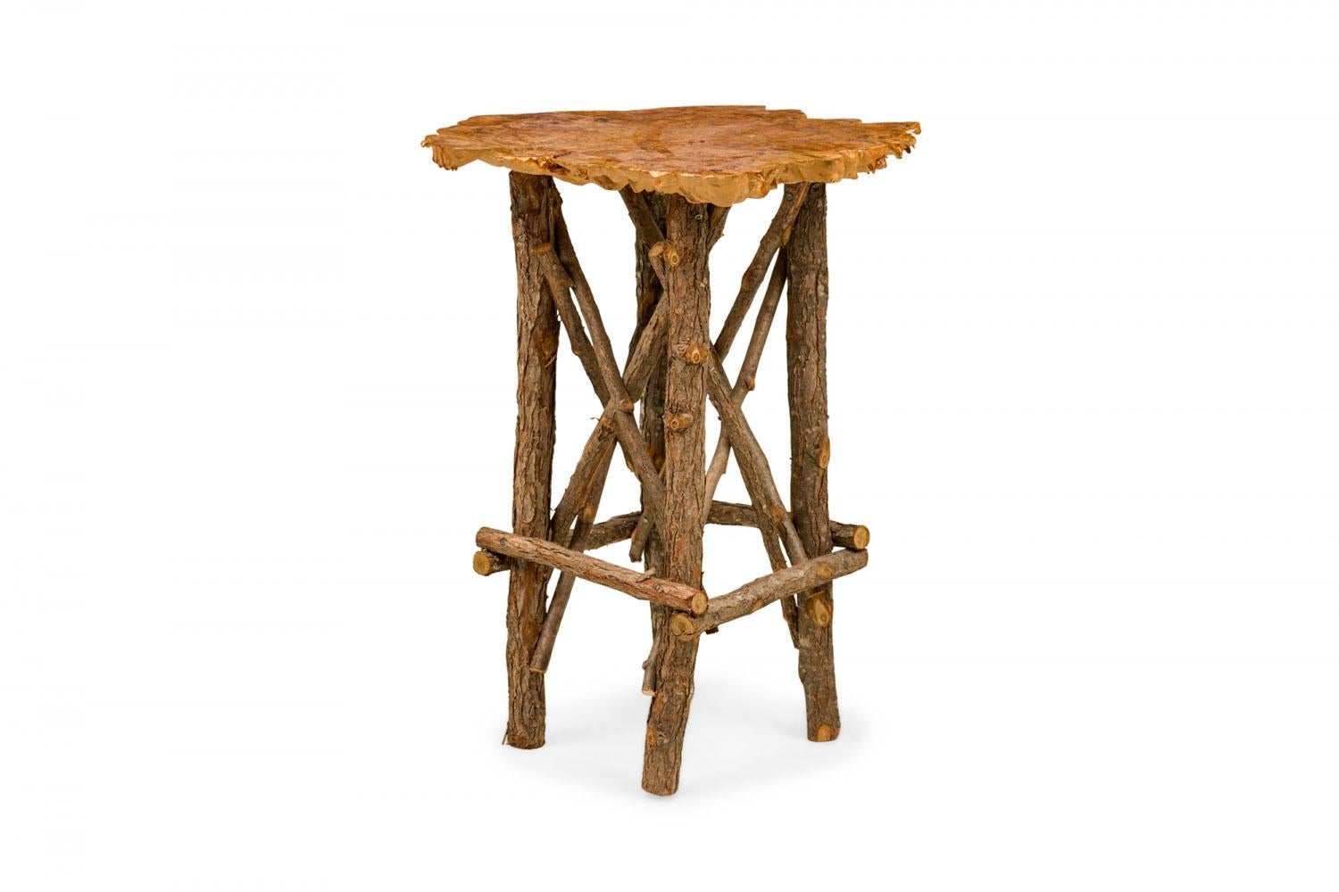 Contemporary Rustic Adirondack end / side table with a petrified wood top with organically scalloped edges supported on a branch base with x-stretchers. (Similar tables: 063373, 063374)