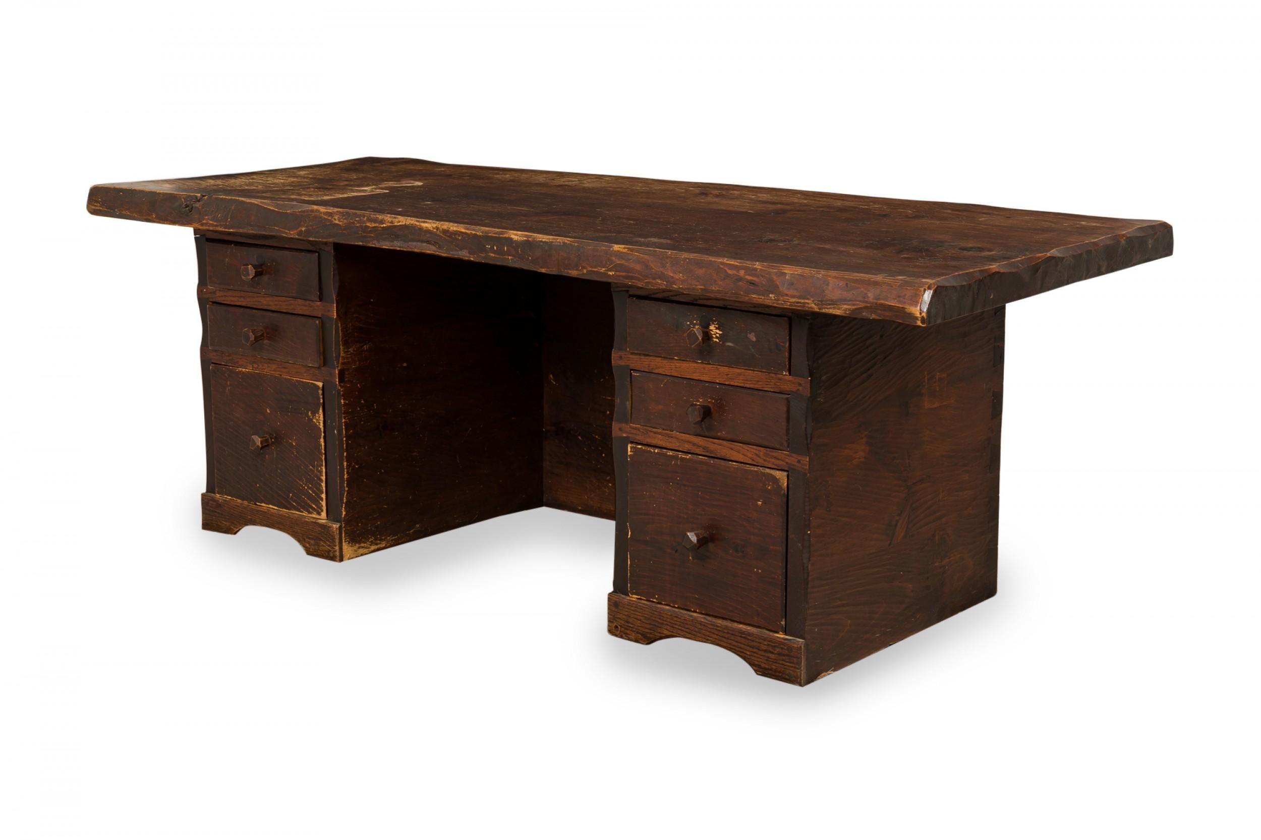Rustic Adirondack (2nd quarter 20th Century) heavy wooden executive desk with a hewn solid wooden desktop supported by two pedestal bases, each containing three drawers with carved wooden drawer pulls and a front privacy panel connected with tusk