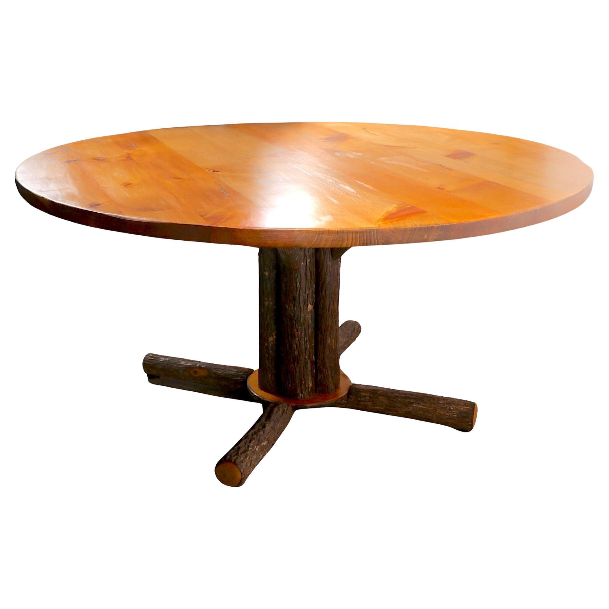 Grand et impressionnant   Table de salle à manger rustique Old Hickory, style Adirondack, c. 2000/2020.
La table présente un épais plateau rond en pin massif, soutenu par un piédestal recouvert d'écorce et doté d'une base à quatre branches.
Cet