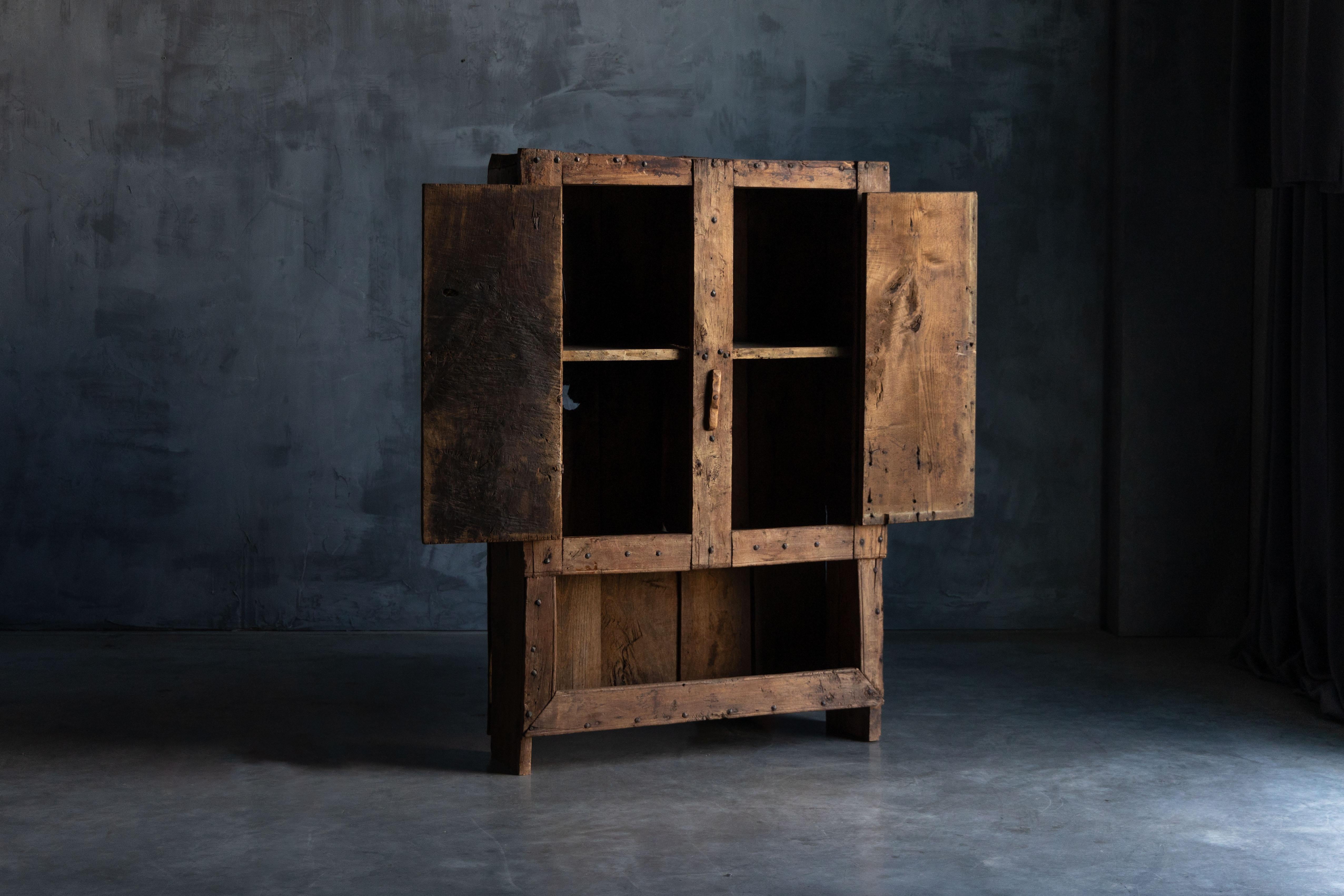 This rustic cabinet from 19th-century Auvergne, France, embodies the essence of Alpine travail populaire craftsmanship. Constructed from richly patinated solid wood, it features hand-forged iron hinges, robust nail detailing, and a simple wooden