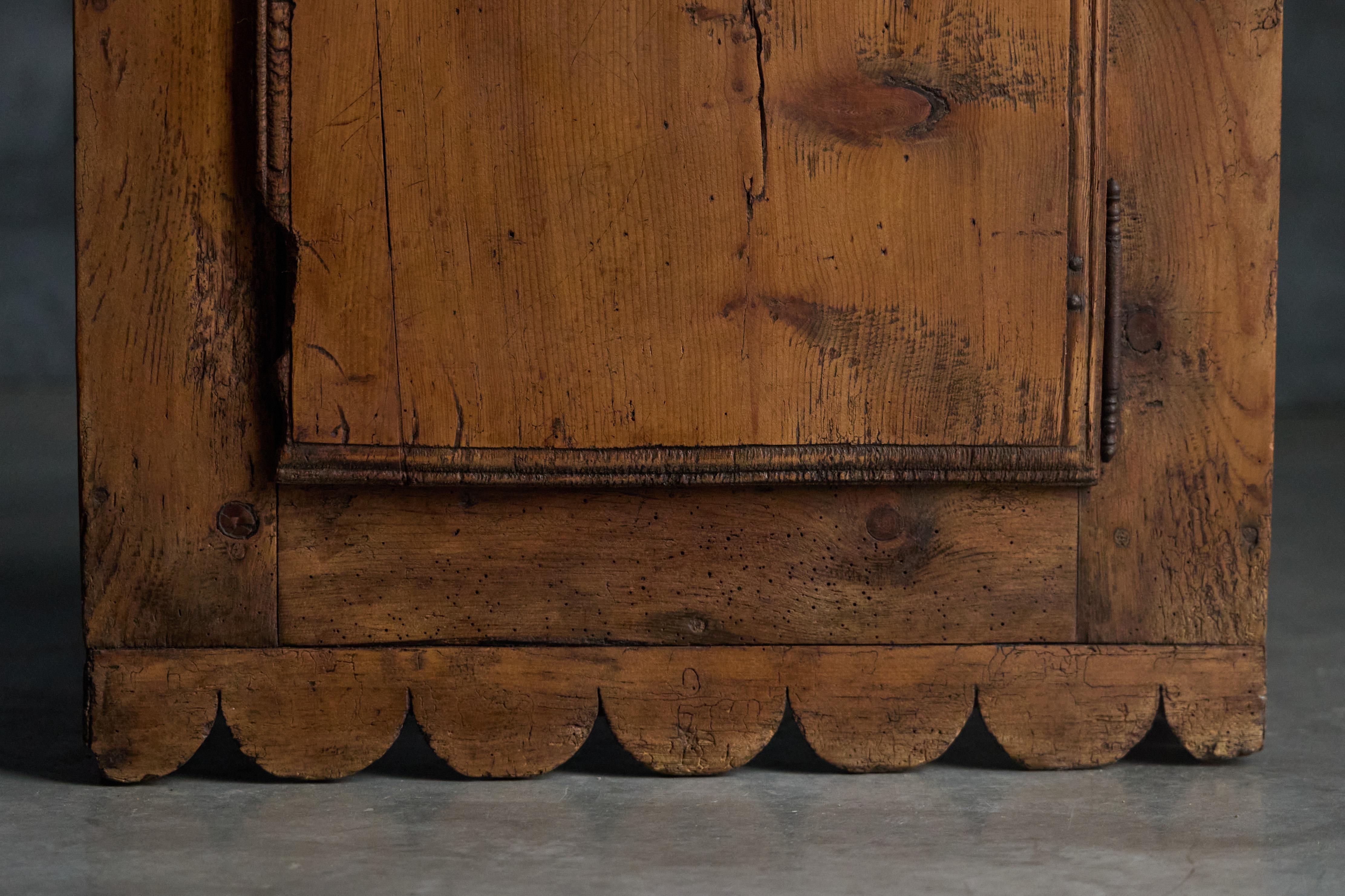 Charmanter, handgefertigter Alpenschrank aus massivem Kiefernholz, der die rustikale Eleganz der savoyischen Volksmöbel unterstreicht. Das Design zeichnet sich durch klare, minimalistische Linien aus, die durch eine schöne Wellenform am unteren Rand