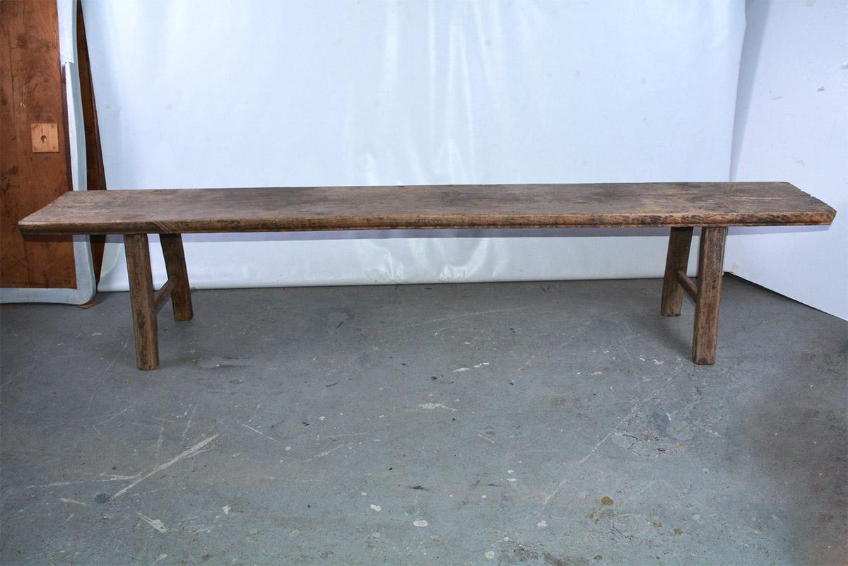 The rustic antique Asian long bench is made of handcrafted teak wood. Stretchers are solidly pegged to the legs, which are pegged to the thick top. The sides are rounded for comfortable seating. Picture the bench on a porch (for potted plants?), sun