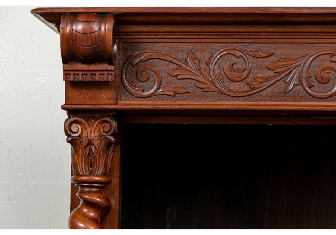 Classic antique barley twist bookcase with a well carved frieze with stippled back and foliate scrolls having a center urn. Open scrolls are above the barley twist supports with leafy capitals. With an oak back and four oak adjustable shelves (one