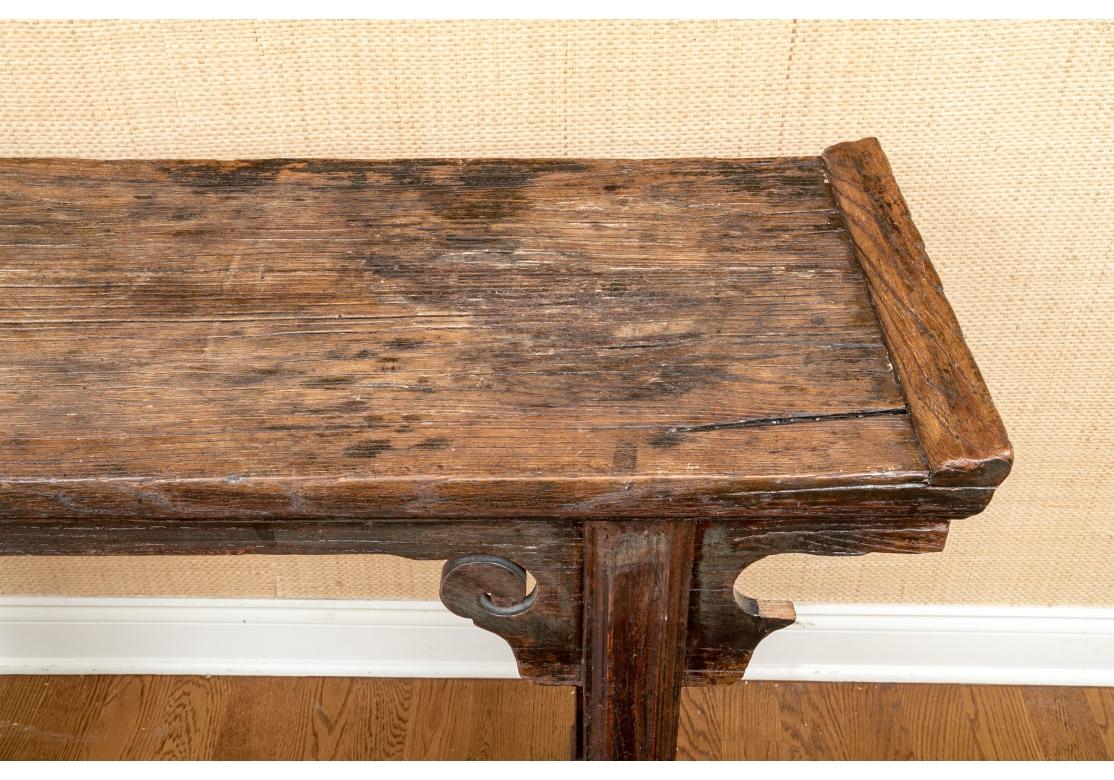 A fine Asian table with aged raised graining which adds texture to the Rustic presentation. Traditional form with upraised ends, scrolled decoration to the apron and sides, good weight and great overall condition. Many uses including Sofa or Hall