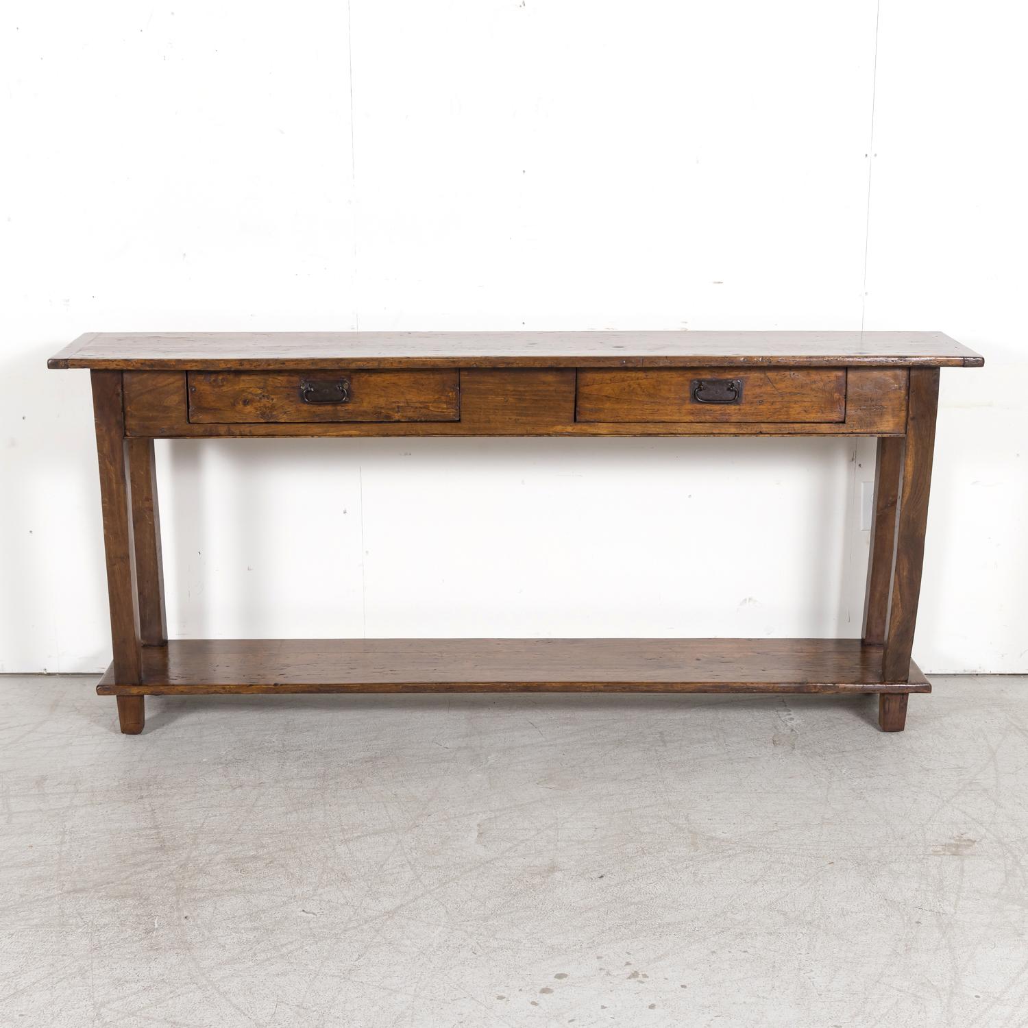 A handsome rustic mid-19th century Country French console table converted from an antique farm table hand crafted in Normandy, circa 1850s. Walnut plank top above a solid oak frame featuring two drawers with drop bail brass handles. Raised on square