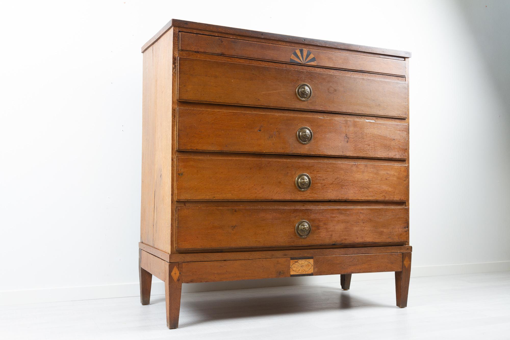 Antique Danish empire commode ca. 1810.
This amazing rustic oak dresser was made in Denmark between 1800 and 1810. The early influence of empire design is seen in the sun burst inlay and the urns on the original cast brass fittings. It features