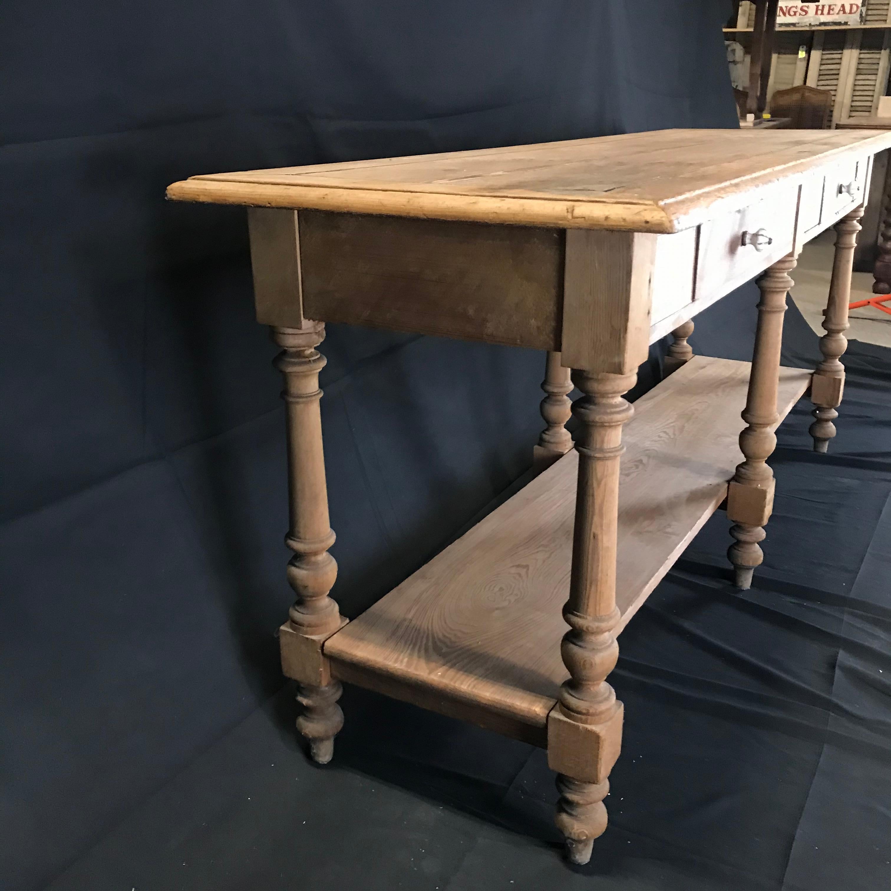 A versatile long narrow rustic French scrubbed pine sofa table, sideboard or credenza with antique ceramic pulls, circa mid-late 1800s. Measures: Skirt 26.25”
#4734.
       