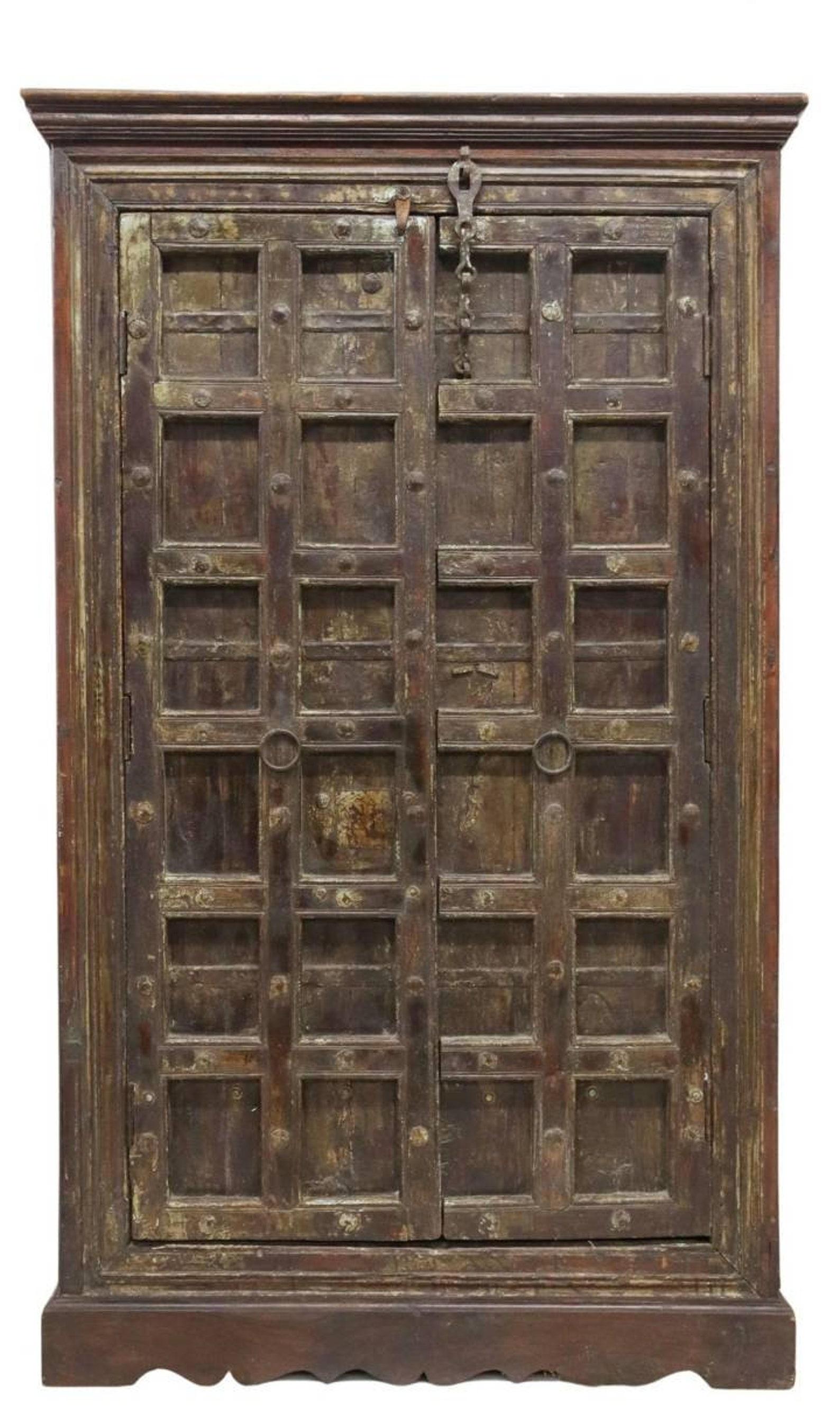 A large and most impressive Indian armoire / cupboard with dark heavily distressed patina.

Born in India in the early 20th century, featuring rustic handmade craftsmanship, solid wood construction, with older reclaimed antique ironwork elements