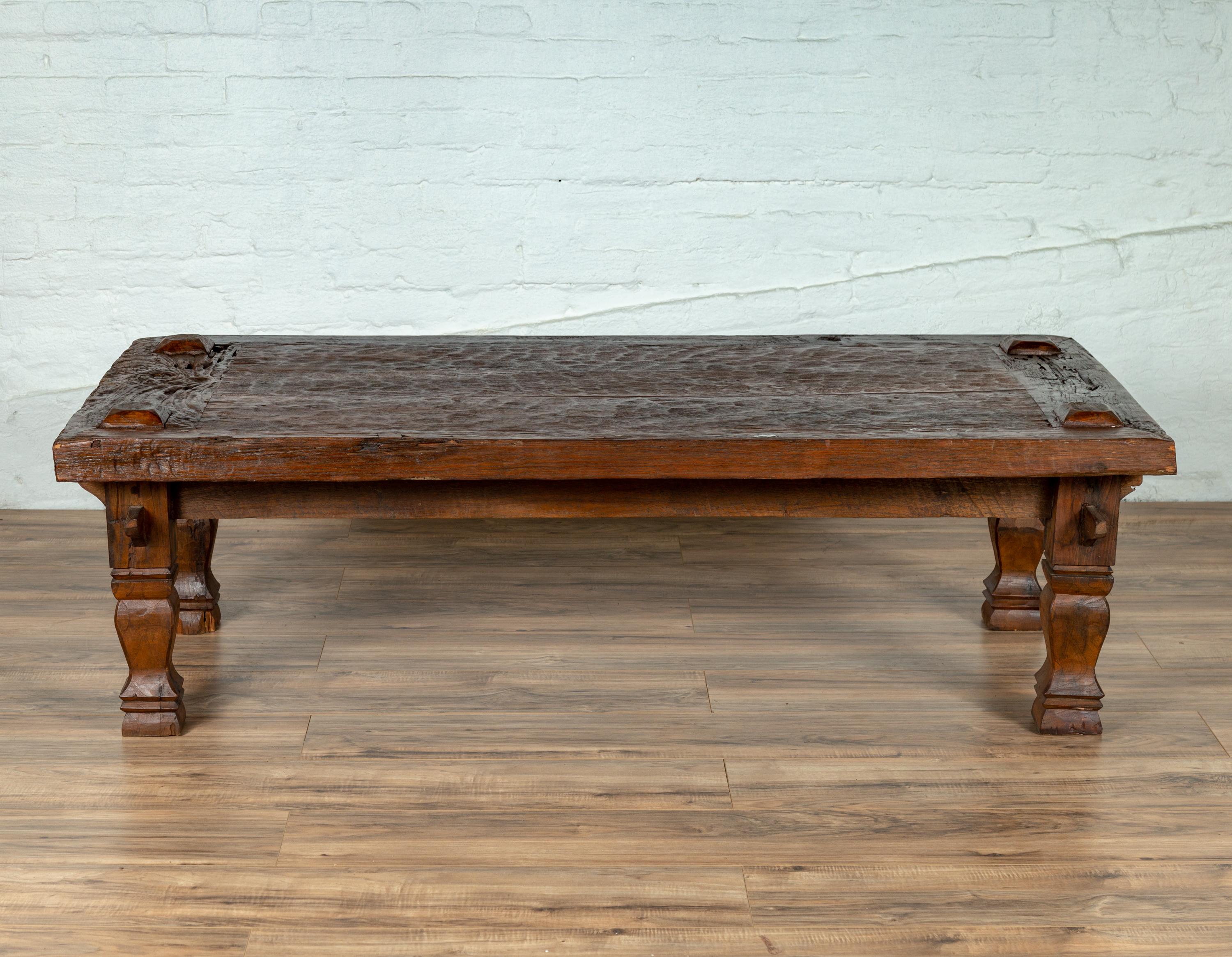 A rustic Javanese antique teak wood coffee table from the early 20th century, made from a tree. Born on the island of Java in the early years of the 20th century, this rustic teak coffee table features a nicely textured rectangular planked top with
