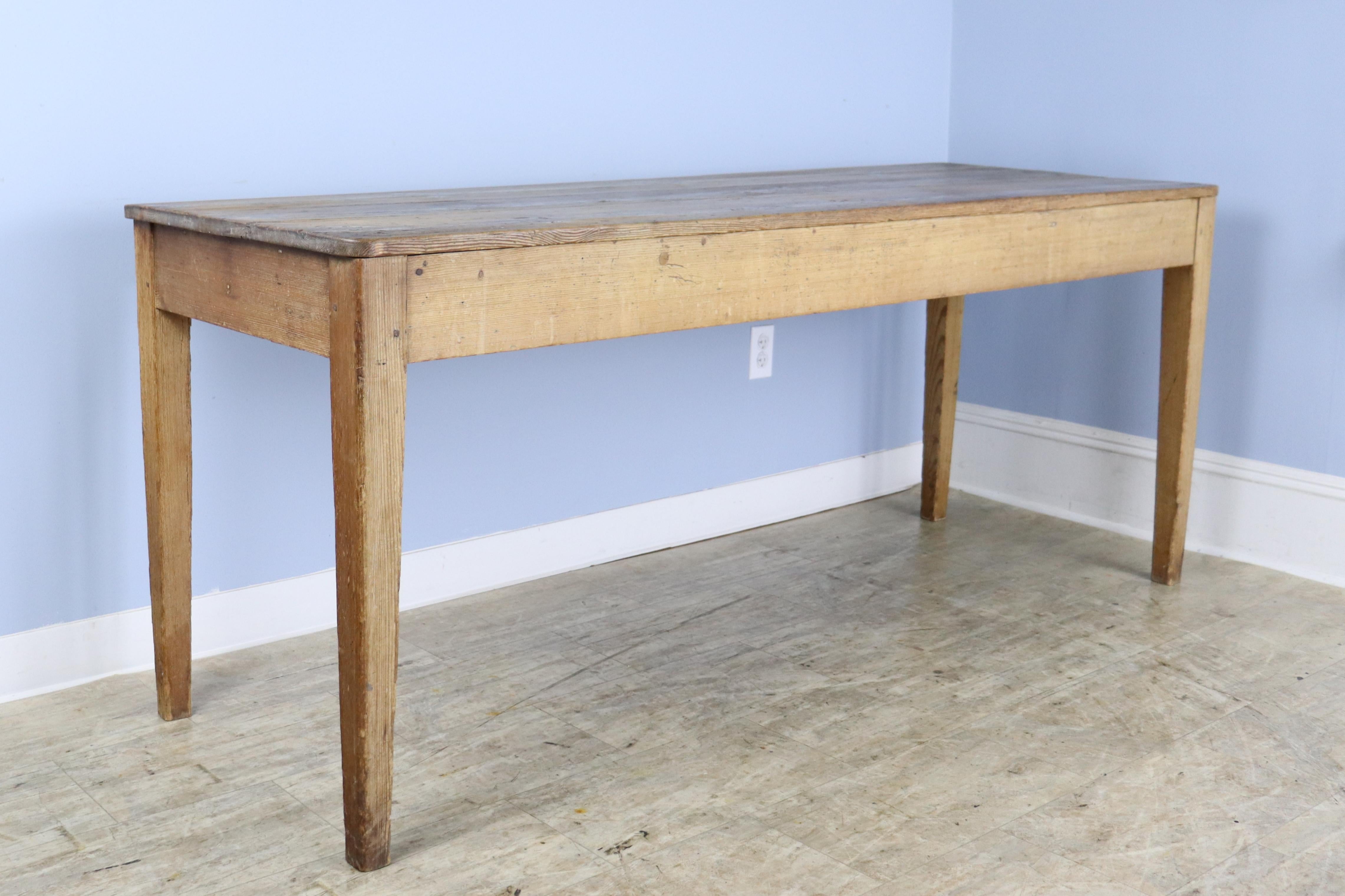 A narrow light pine farm table with good pine grain and a classic silhouette.  Legs are nicely pegged at the apron.  The apron height of 25 inches is good for knees, and there are 70.5 inches between the legs on the long side.