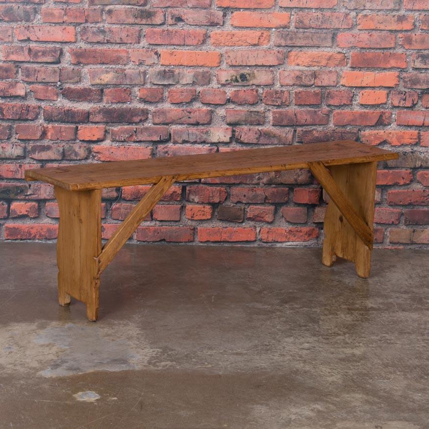 This charming antique pine bench glows with a wax finish that enhances the patina of the aged natural pine. Notice the exposed mortise and tenon construction with diagonal supports that are dovetailed flush to the back to make this country piece